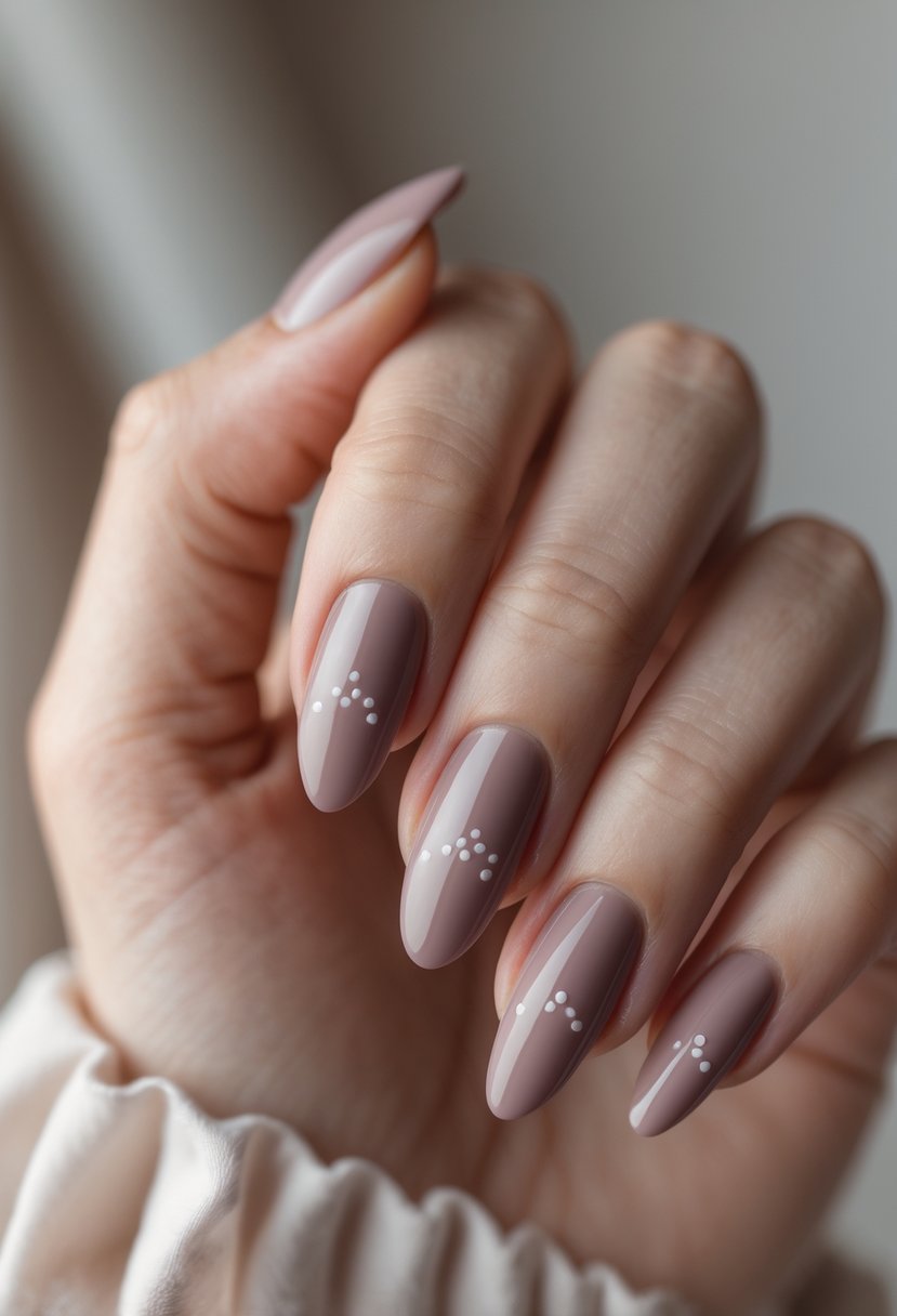 Close-up of a hand with dusty rose colored nails featuring small minimalist dot designs.