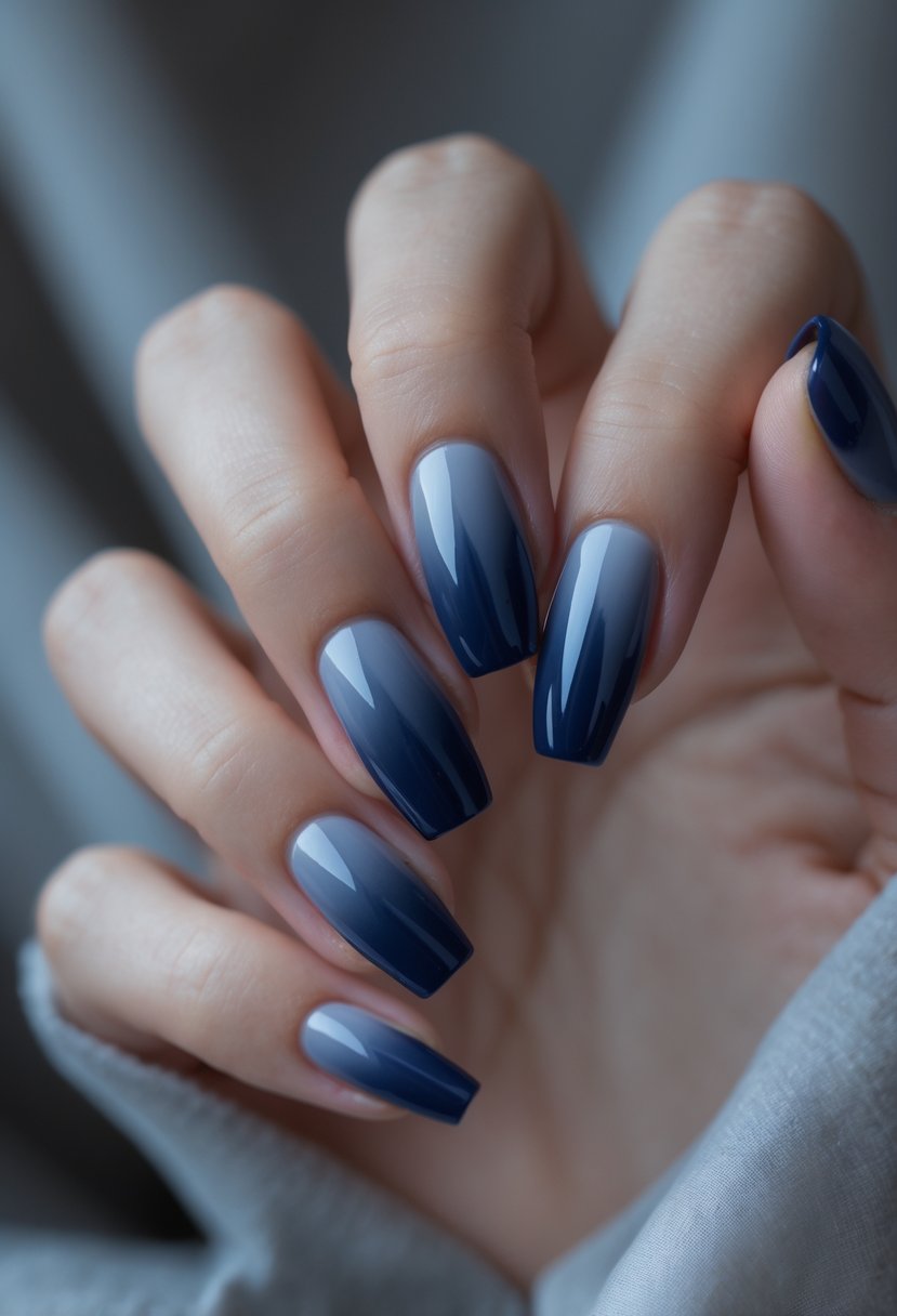 Close-up of hands with navy blue ombre manicured nails against a soft neutral background.