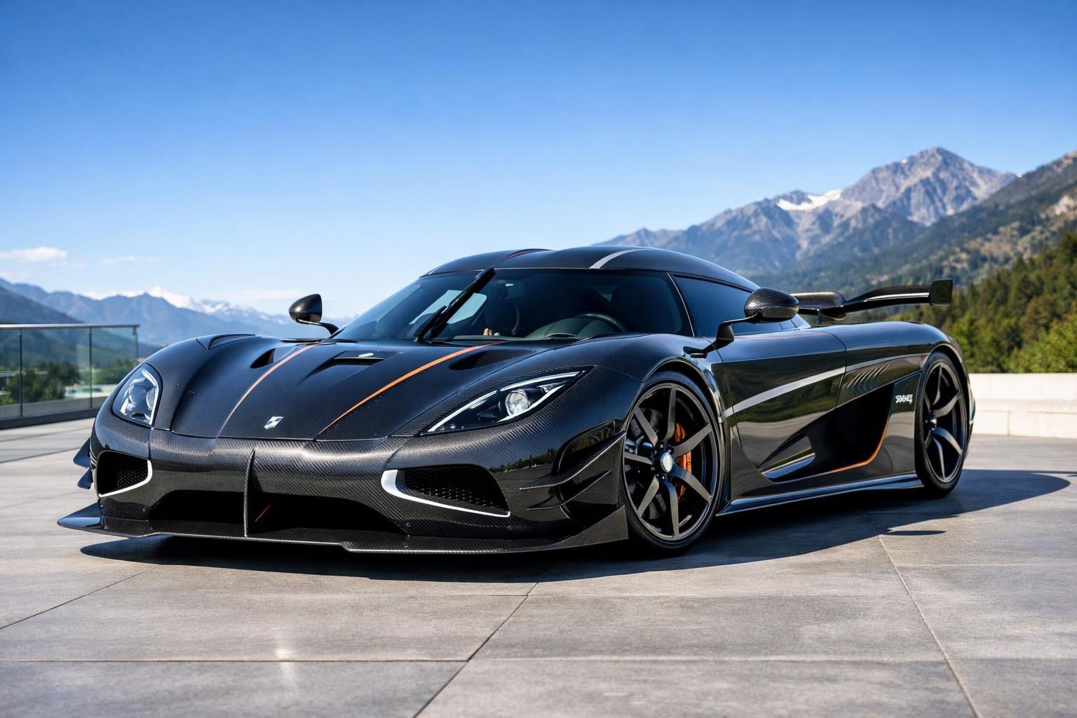 Mobil sport Koenigsegg Agera RS berwarna hitam mengkilap diparkir di jalan masuk modern dengan latar belakang pegunungan dan langit cerah.