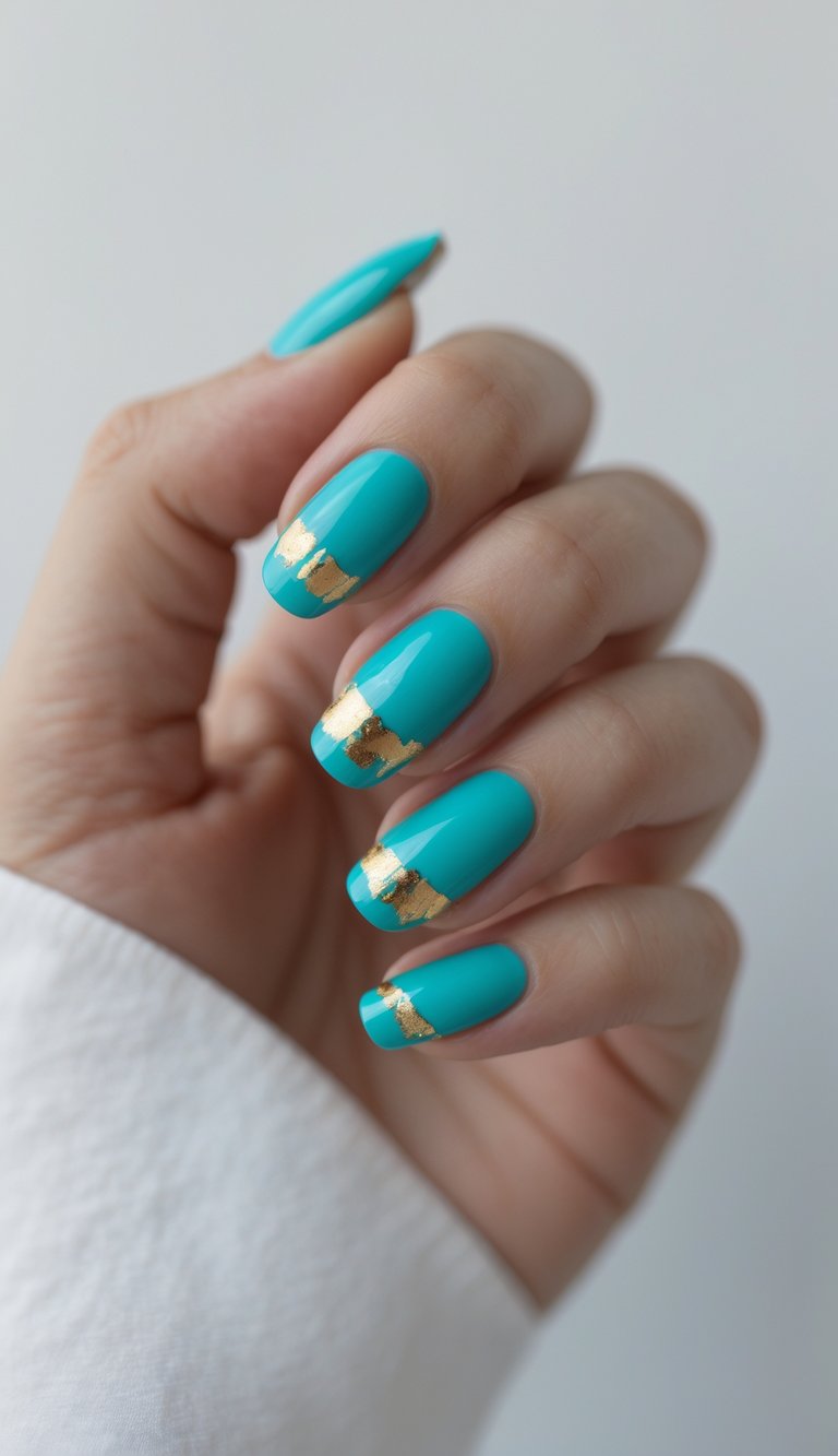 Close-up of one hand with turquoise nails featuring small gold foil accents against a white background.