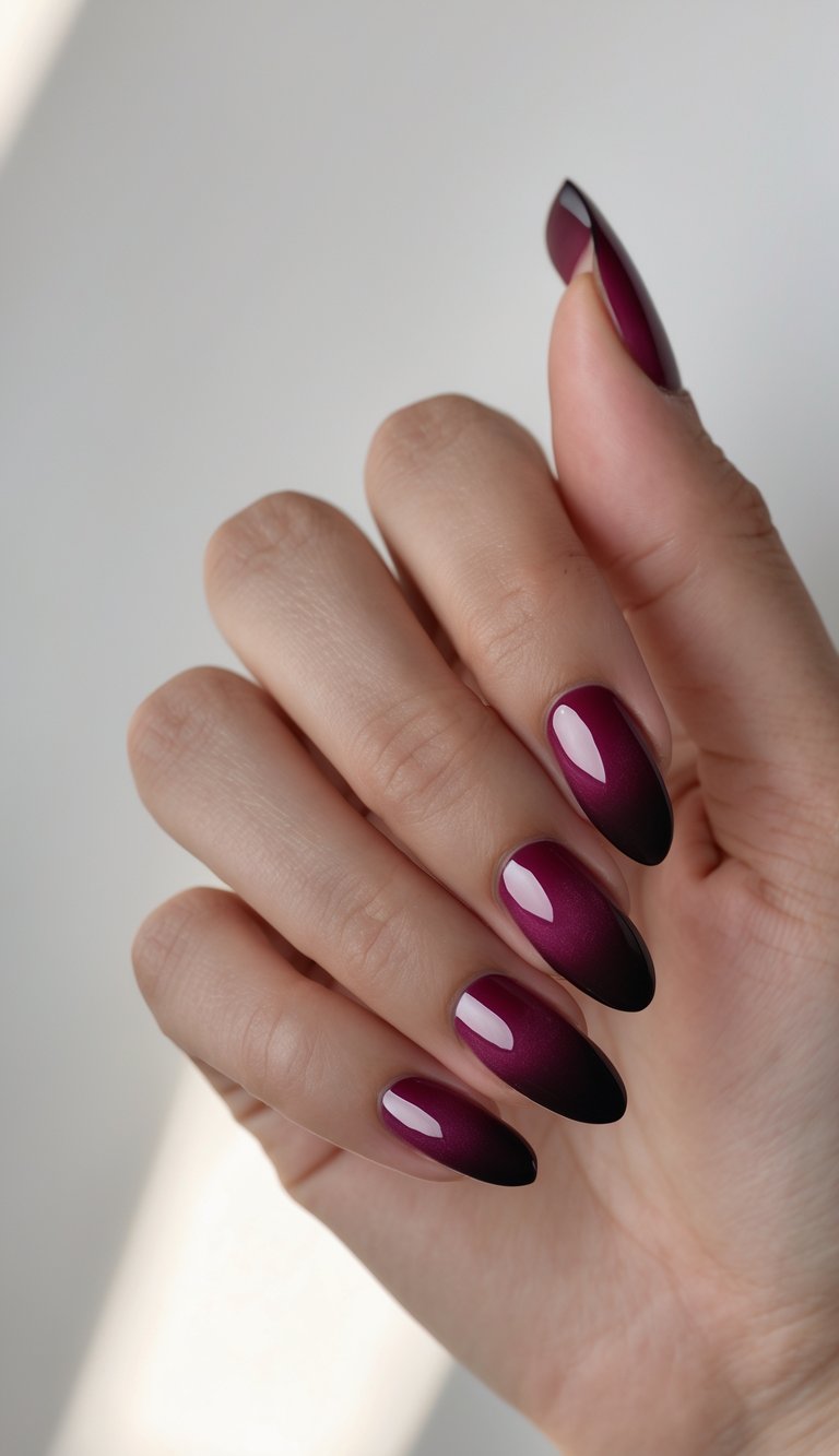 Close-up of one hand with burgundy ombré fade nails against a white background.