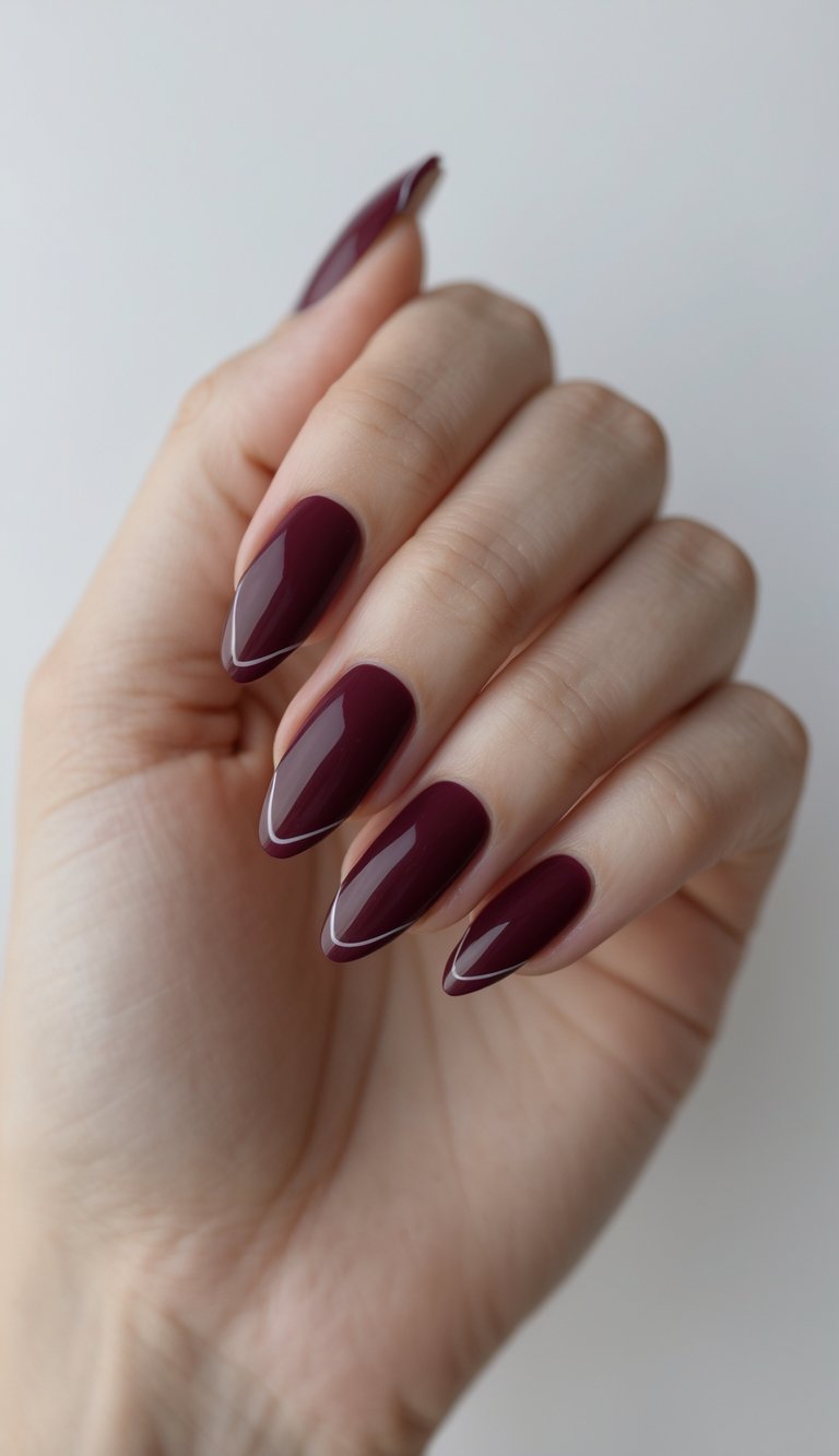 Close-up of one hand with burgundy French almond-shaped nails against a white background.