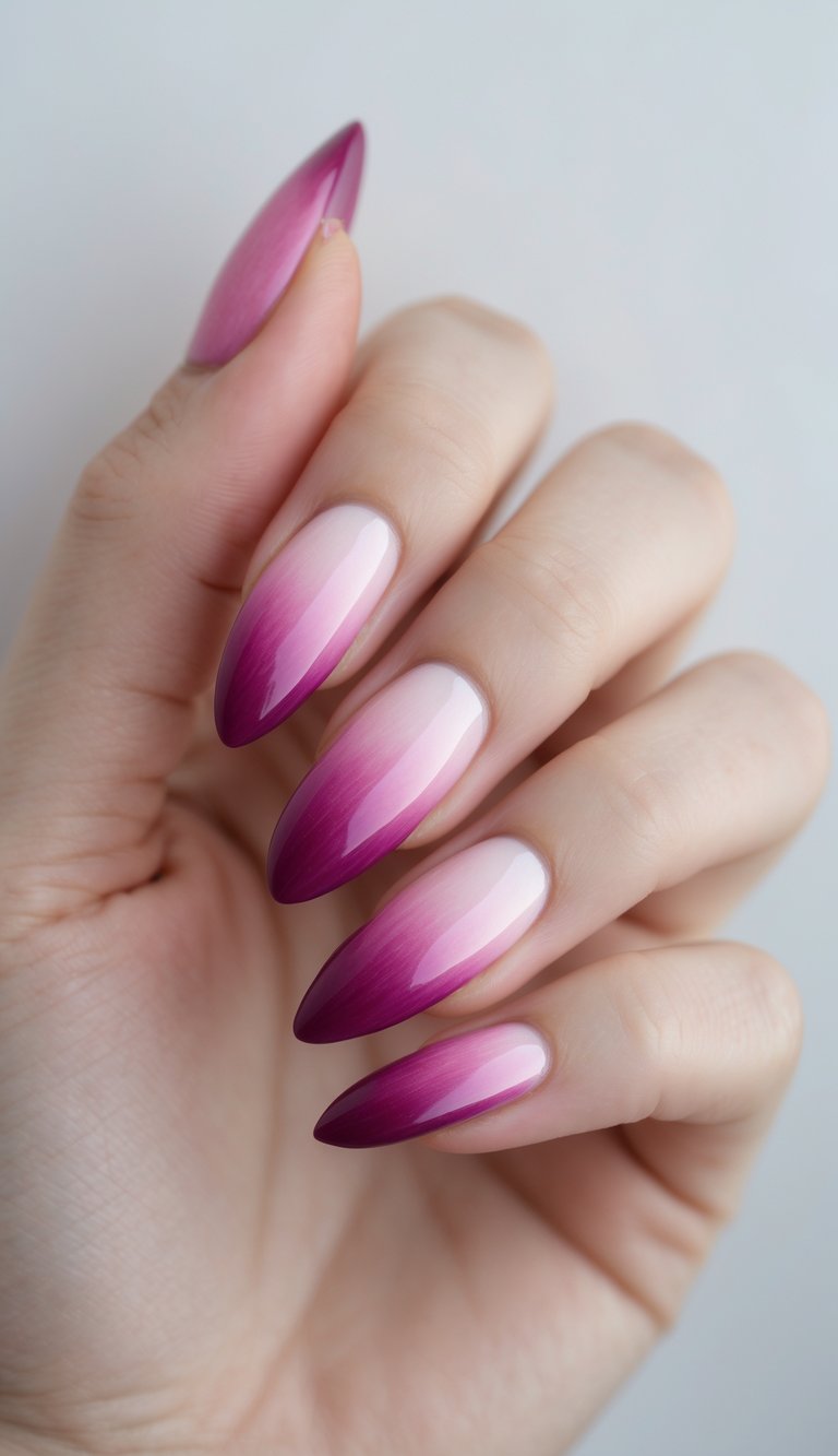 Close-up of one hand with almond-shaped nails featuring a magenta ombre design against a white background.