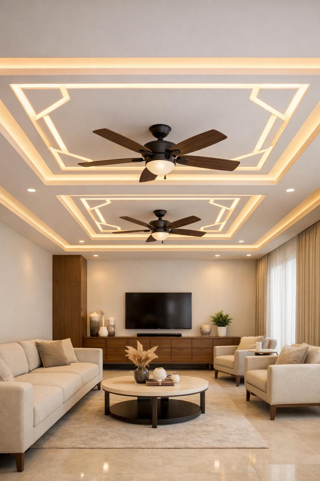 A spacious living hall with two ceiling fans and a modern false ceiling featuring recessed profile lighting and geometric patterns.