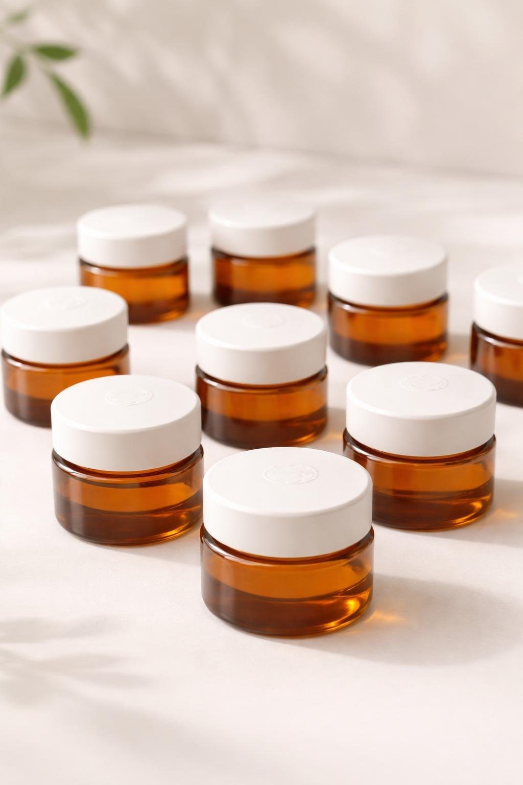 A group of small amber glass jars with white lids arranged on a light surface.