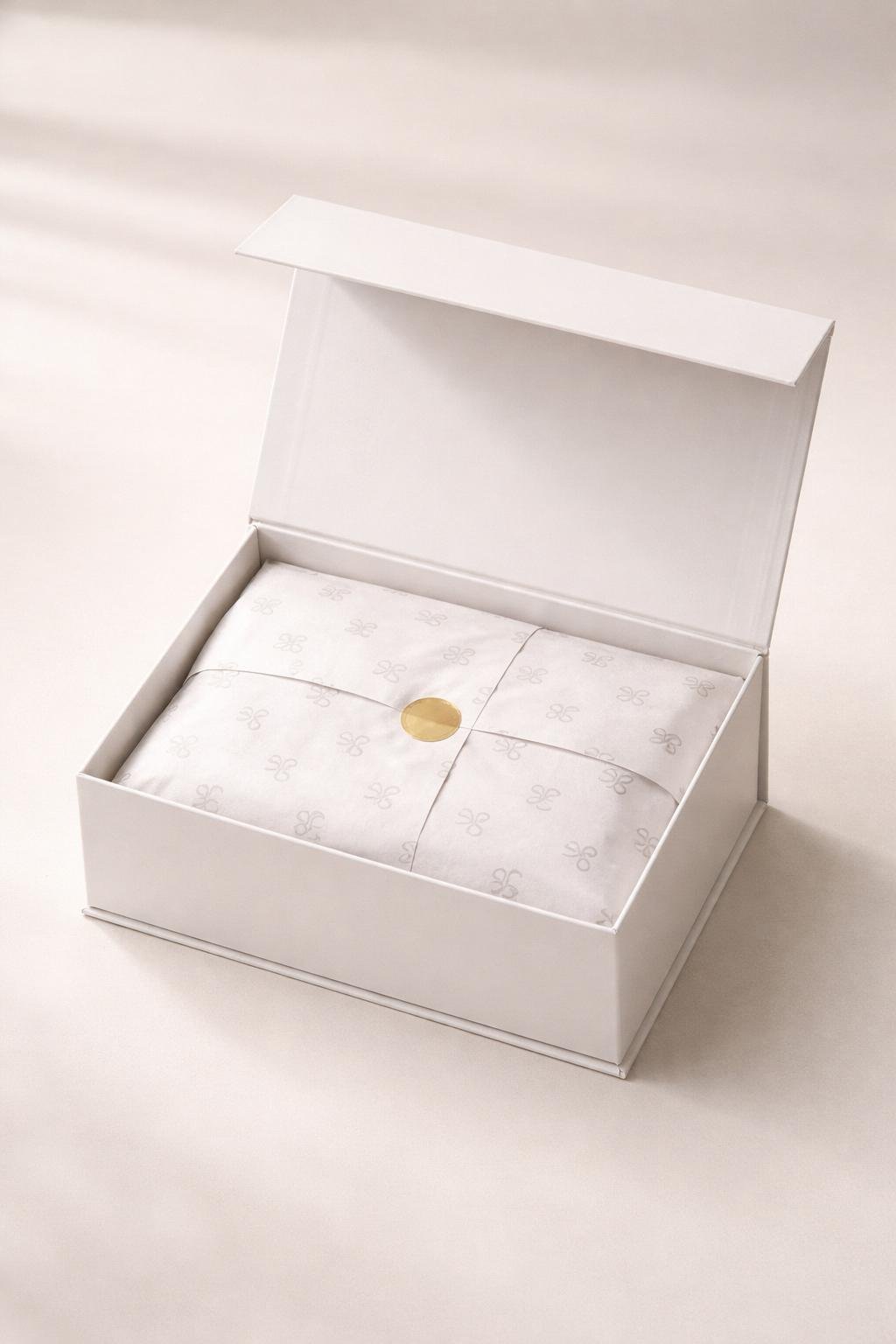 An open rigid gift box with magnetic closure showing neatly folded custom logo tissue paper inside.