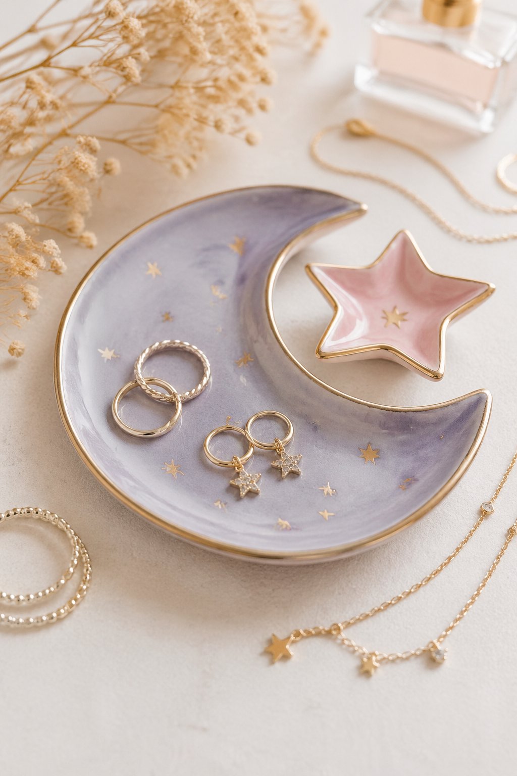 A crescent moon and star-shaped clay trinket tray holding small jewelry pieces on a neutral surface.