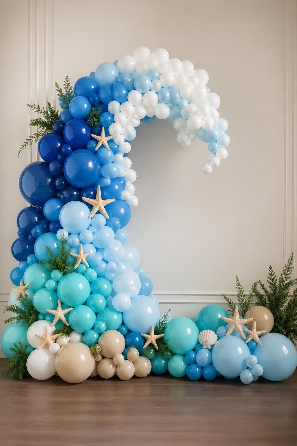 A balloon garland shaped like ocean waves in blue and white colors decorating a wall for a baby shower.
