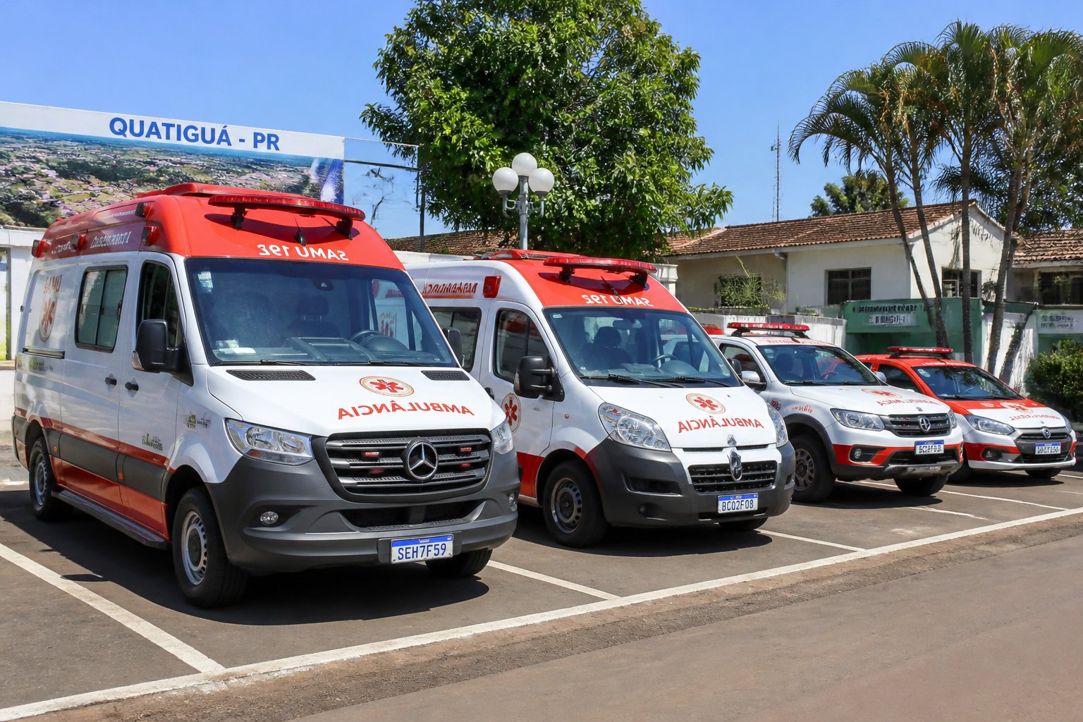 Vários tipos de ambulâncias estacionadas ao ar livre em Quatiguá durante o dia, com prédios e árvores ao fundo.