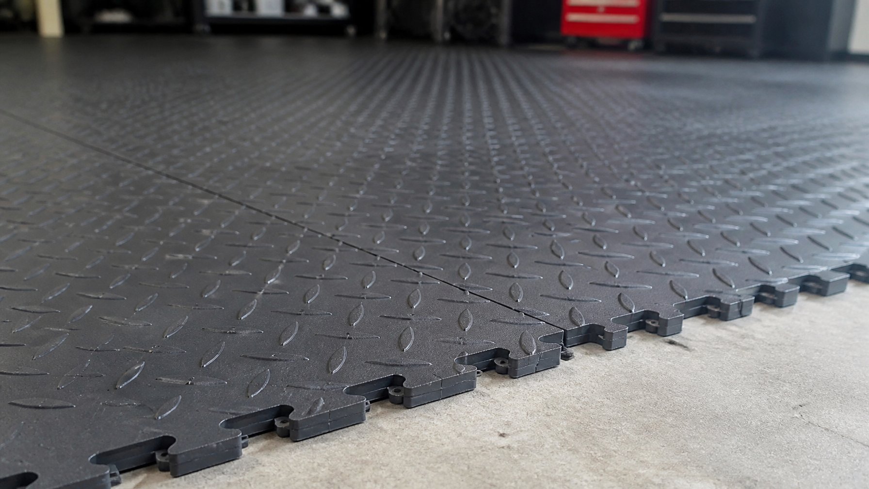 Close-up of charcoal-colored interlocking PVC garage floor tiles in a clean garage setting.