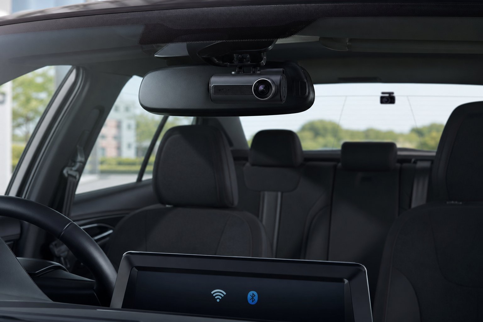 Interior of a car showing the Thinkware Q200 front dash camera mounted behind the rearview mirror and the rear camera visible through the rear window.