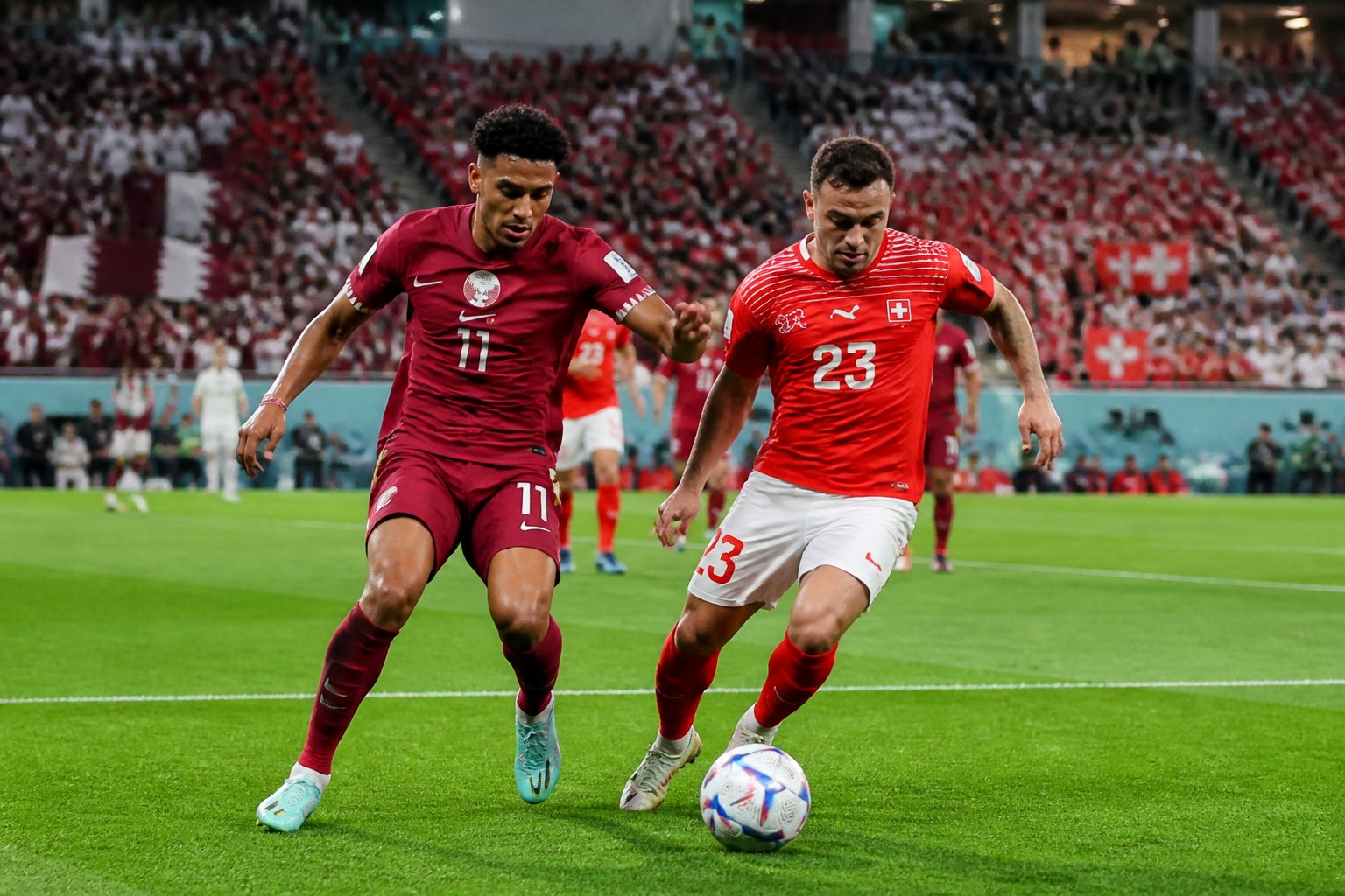 Katar ve İsviçre futbol takımları arasında bir Dünya Kupası maçında, oyuncular top için mücadele ediyor.