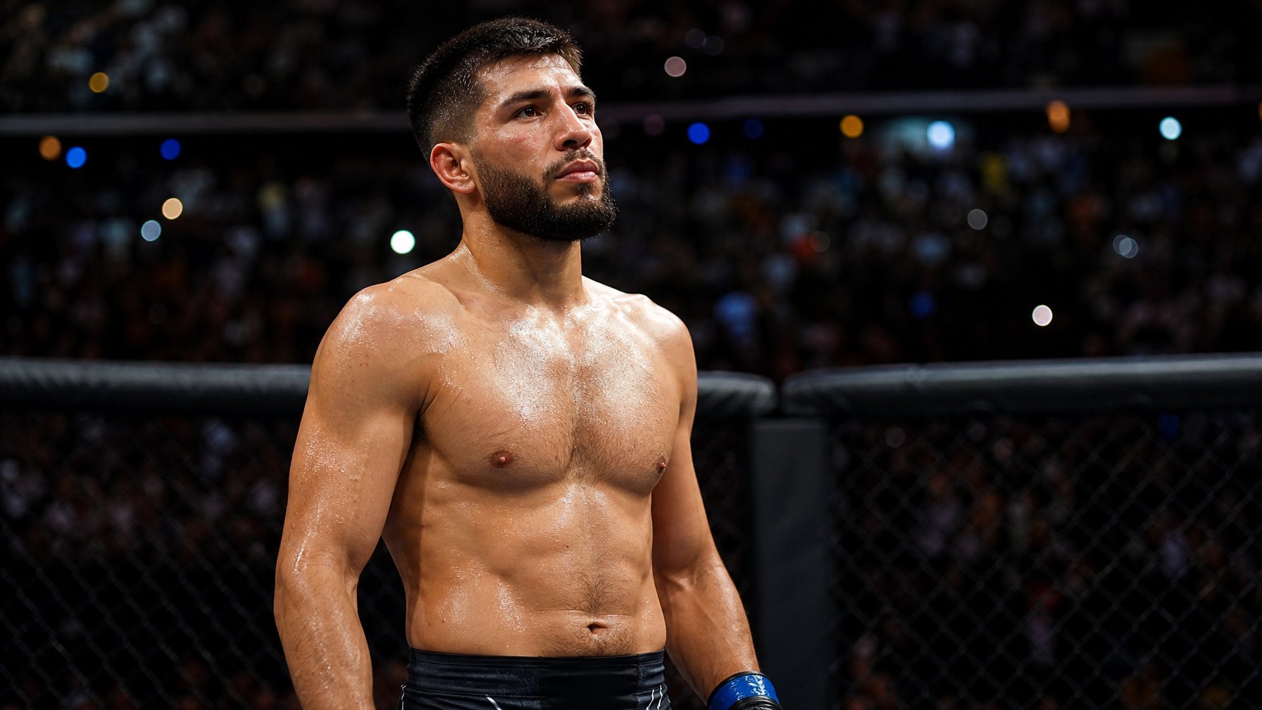 Seorang petarung MMA pria berdiri di dalam kandang octagon dengan ekspresi fokus dan latar belakang penonton kabur.