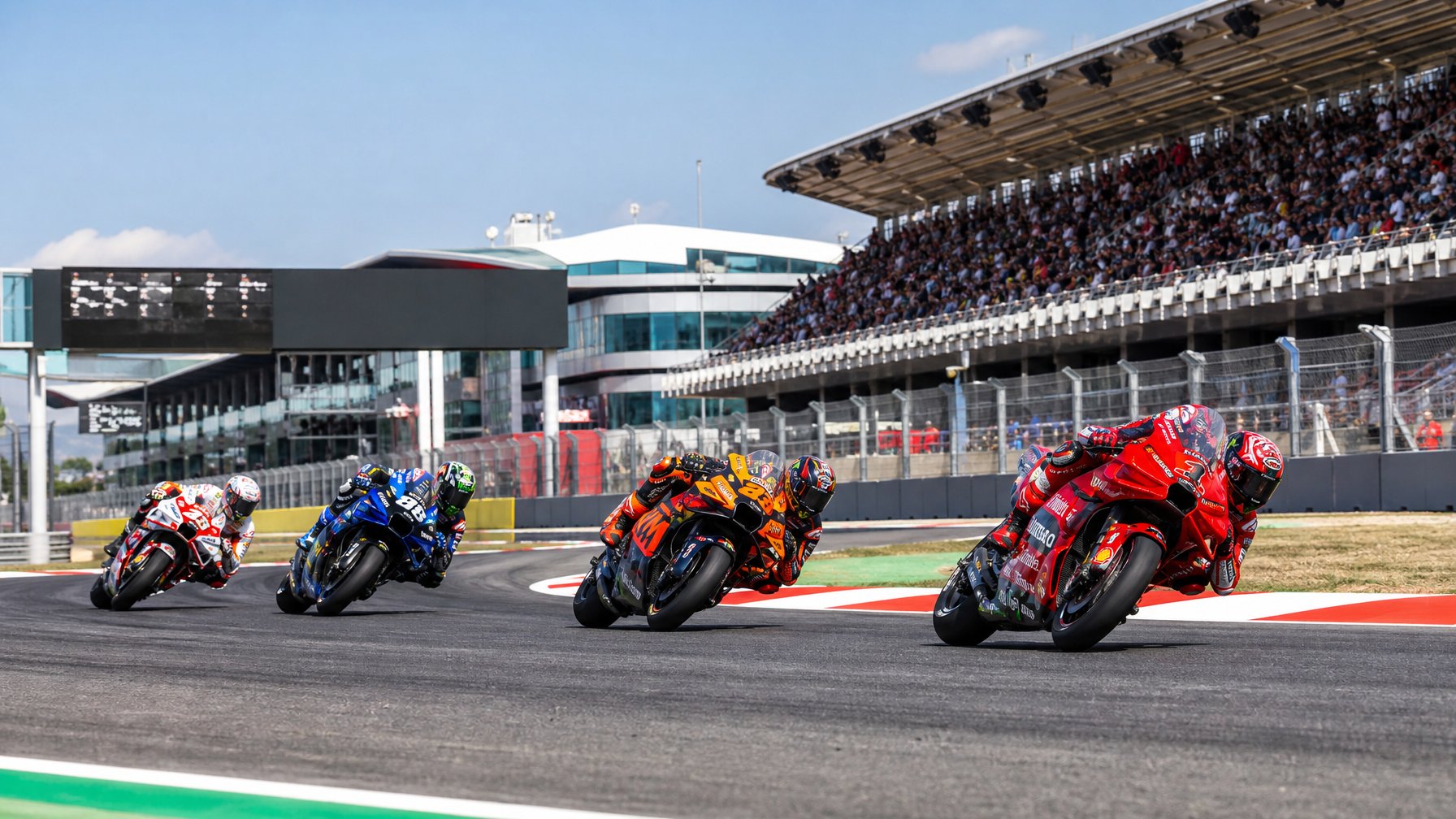 Lomba balap motor MotoGP dengan empat motor dari Ducati, KTM, Yamaha, dan Honda melaju di sirkuit balap yang modern dan ramai penonton.