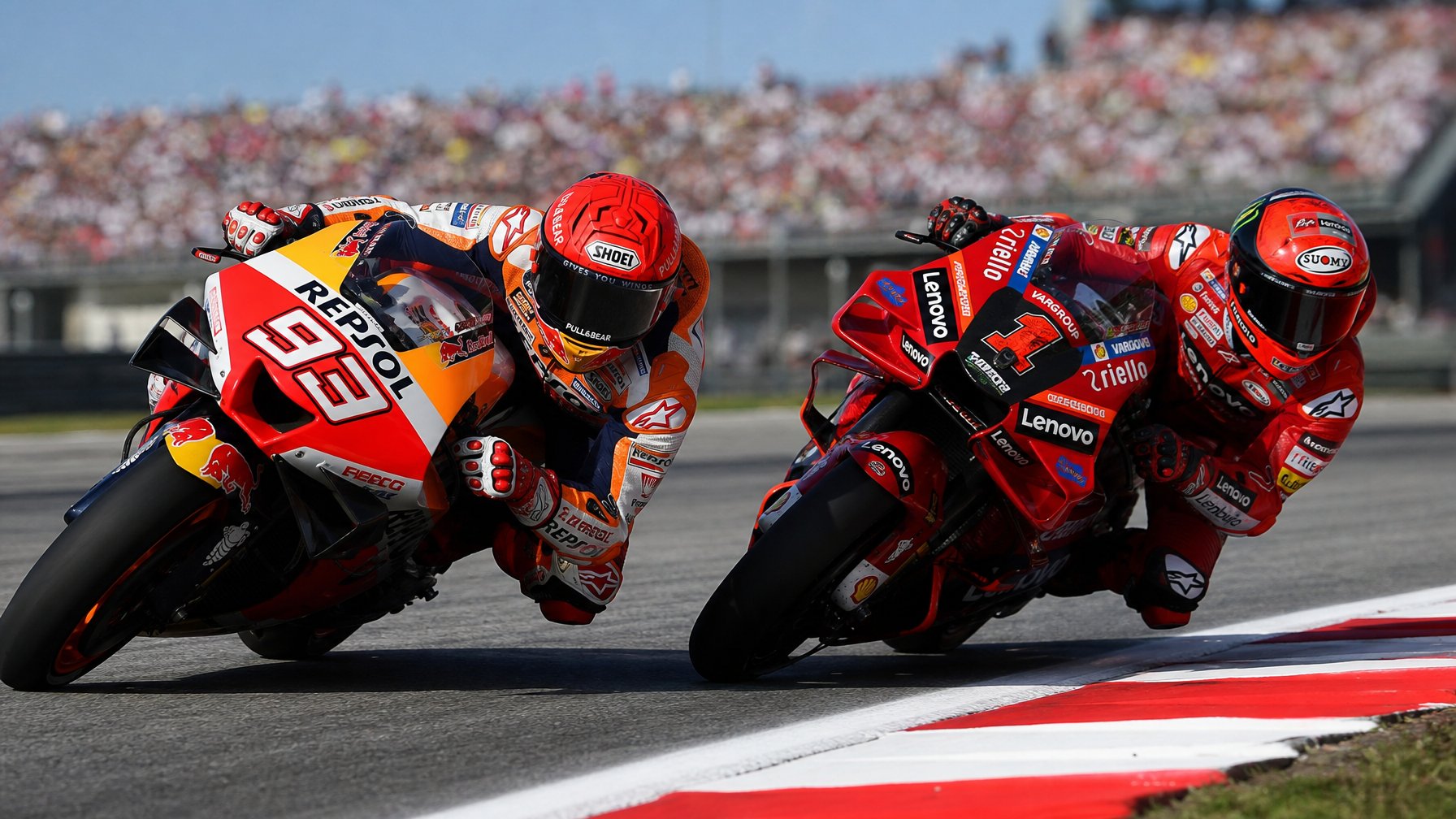 Dua pembalap MotoGP sedang bersaing ketat di tikungan tajam di lintasan balap dengan penonton di latar belakang.