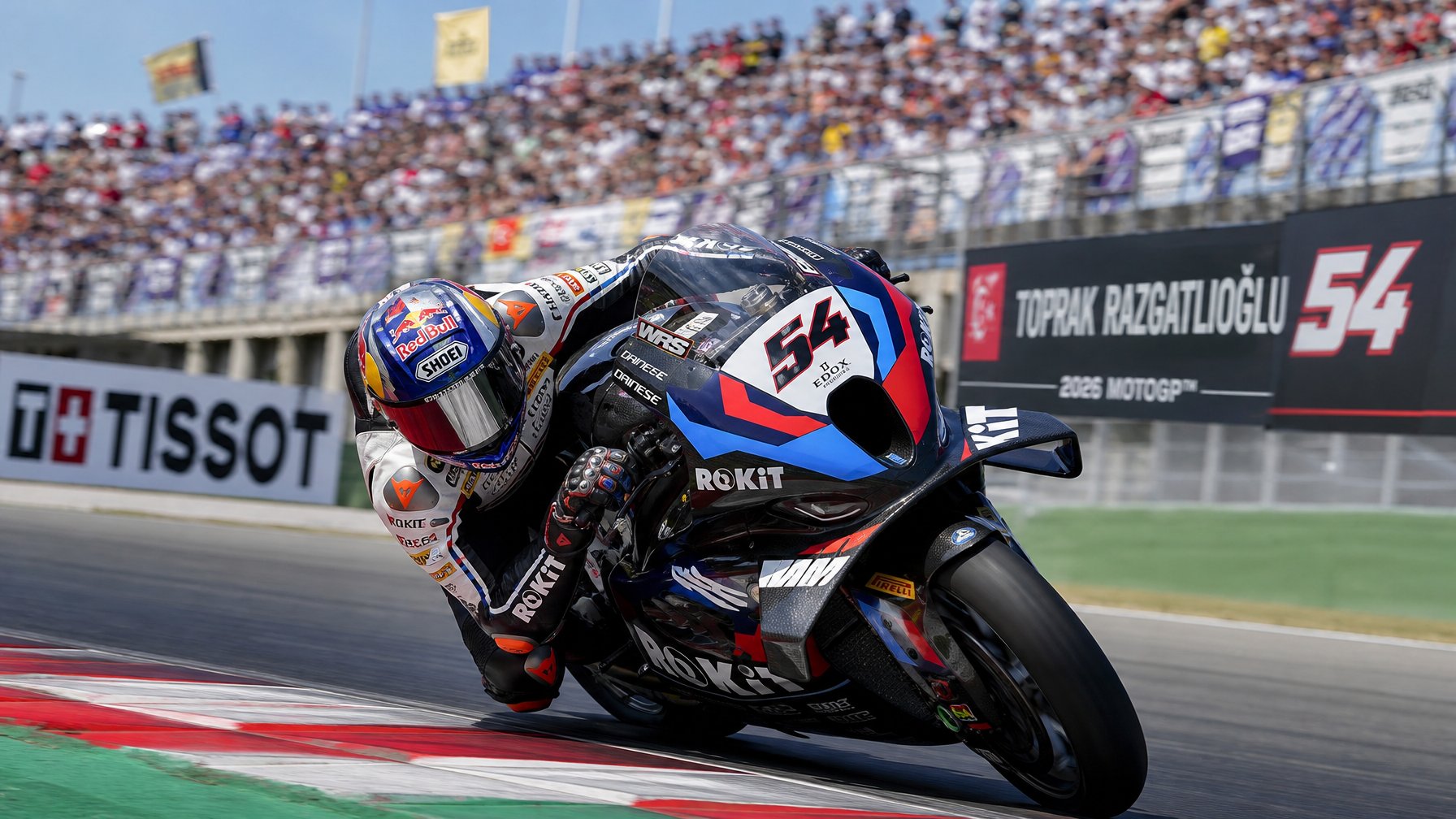 Pembalap MotoGP Toprak Razgatlıoğlu sedang menikung dengan kecepatan tinggi di lintasan balap di depan penonton yang bersorak.
