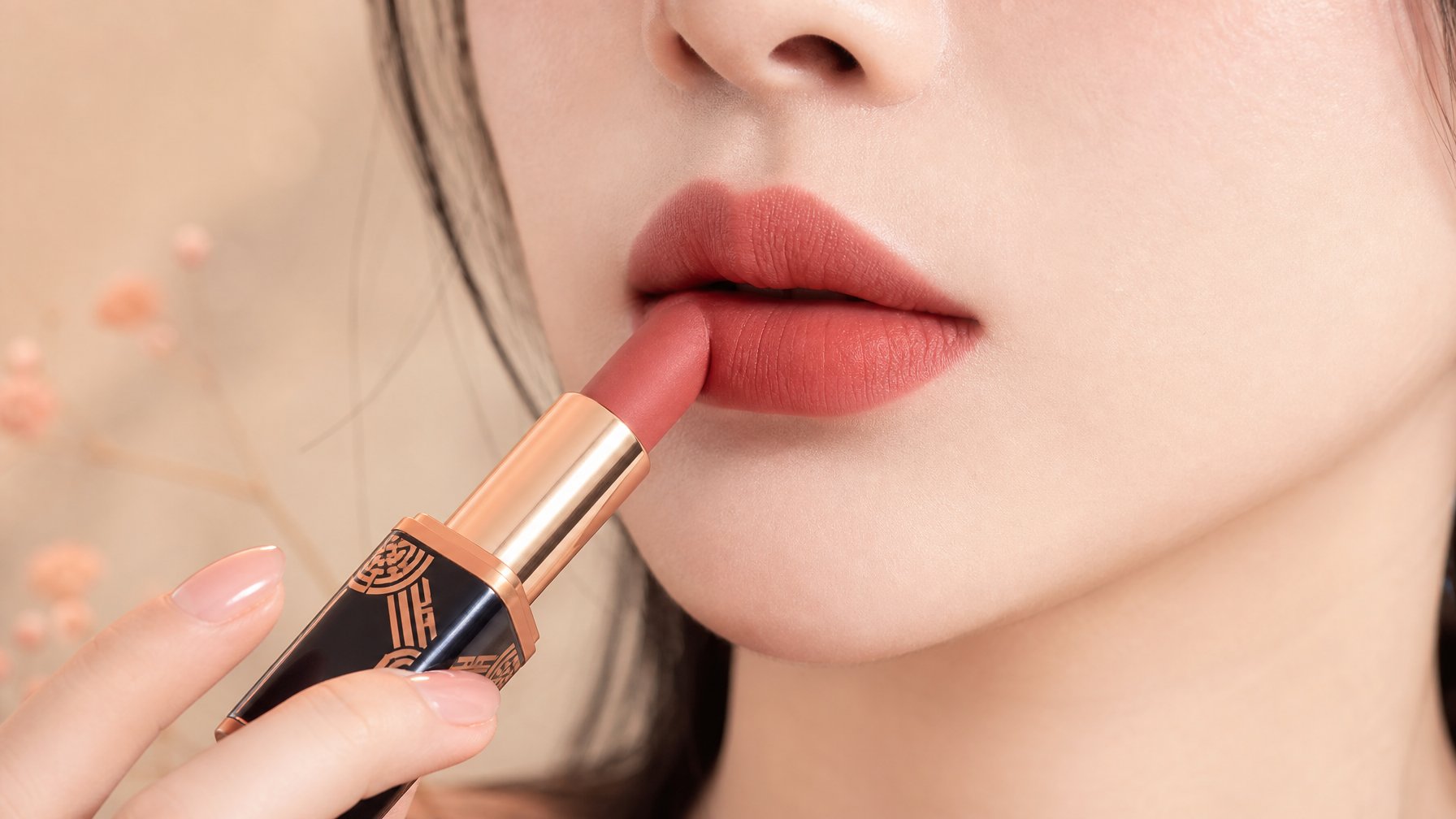 Close-up bibir wanita sedang mengaplikasikan lipstik matte dengan warna yang halus dan lembap.