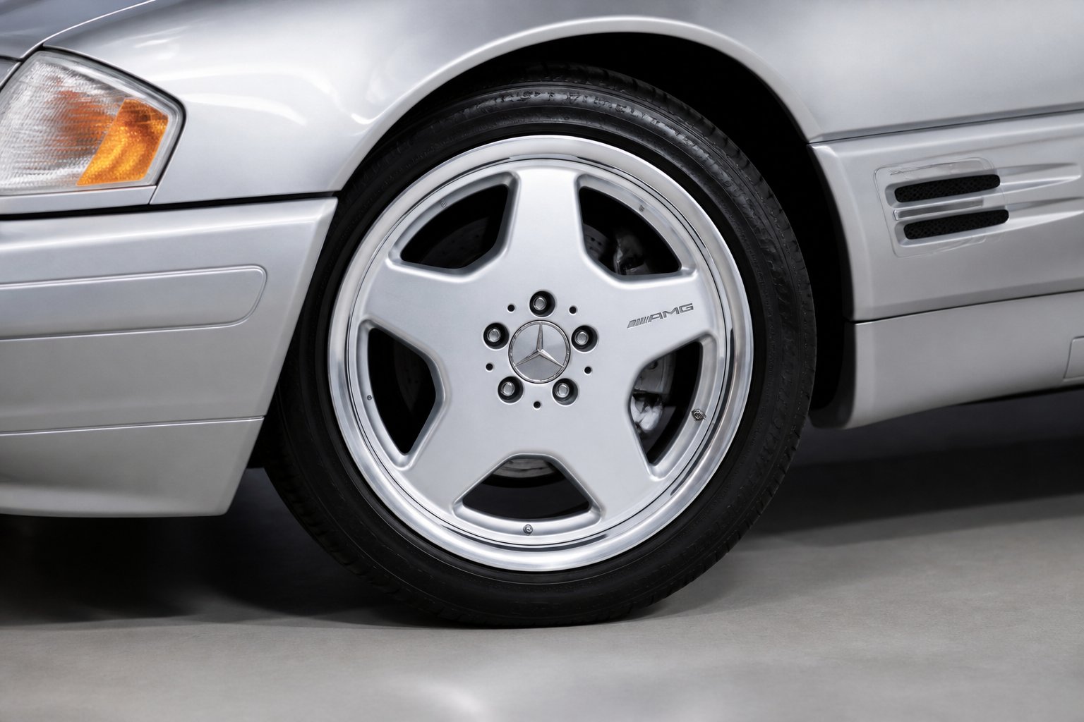 Close-up of a silver 18-inch car wheel mounted on a tire with a blurred background.