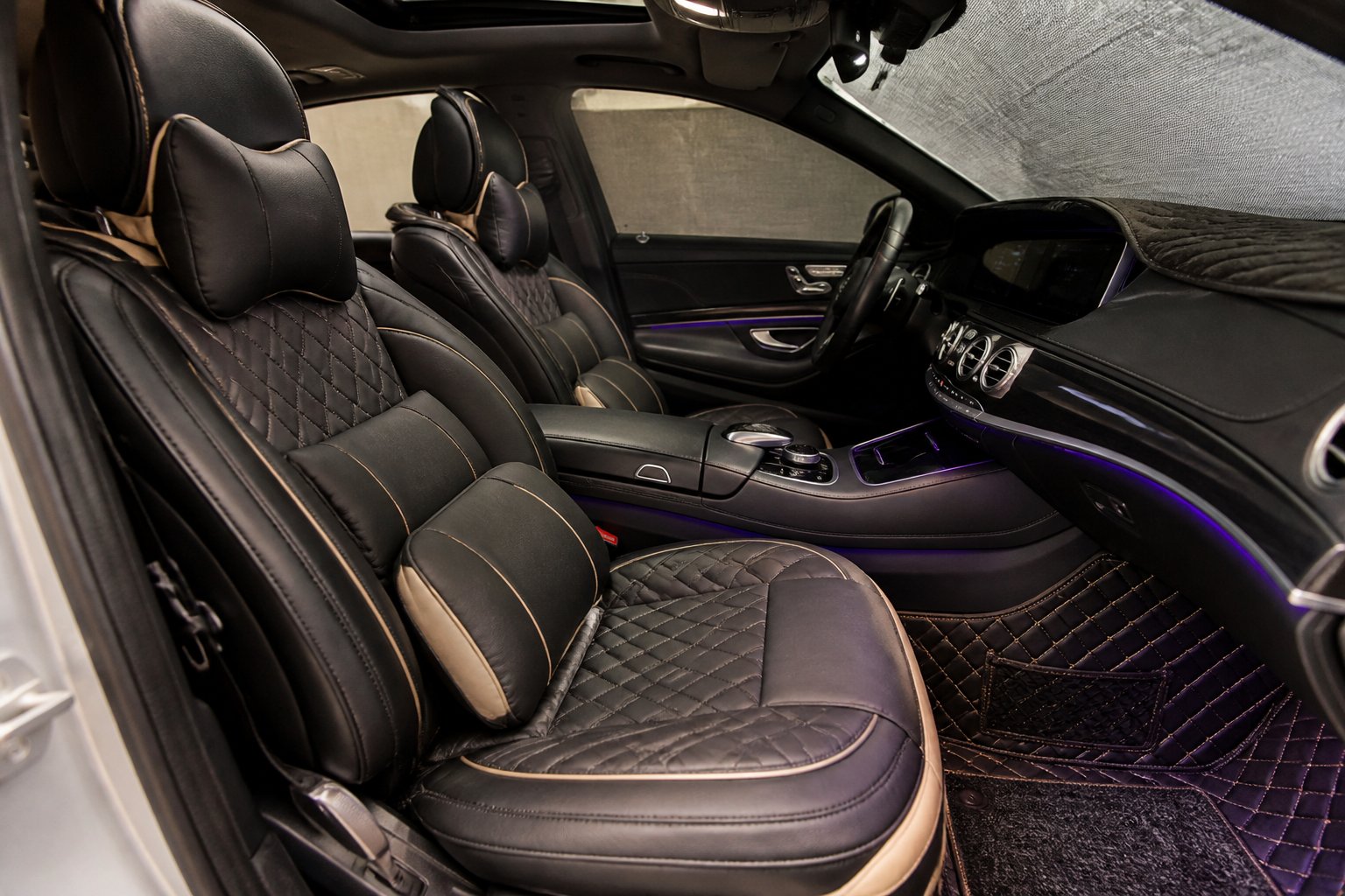 Interior of a Mercedes-Benz car showing upgraded seats, floor mats, steering wheel cover, and dashboard accessories.