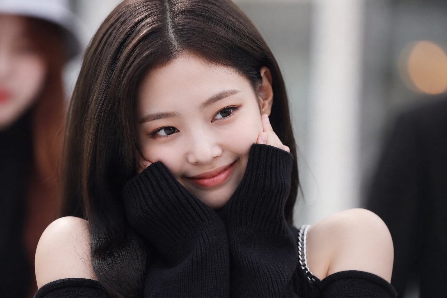 A young Asian woman with a warm smile and expressive eyes, wearing fashionable clothing, looking playfully at the camera against a softly blurred background.