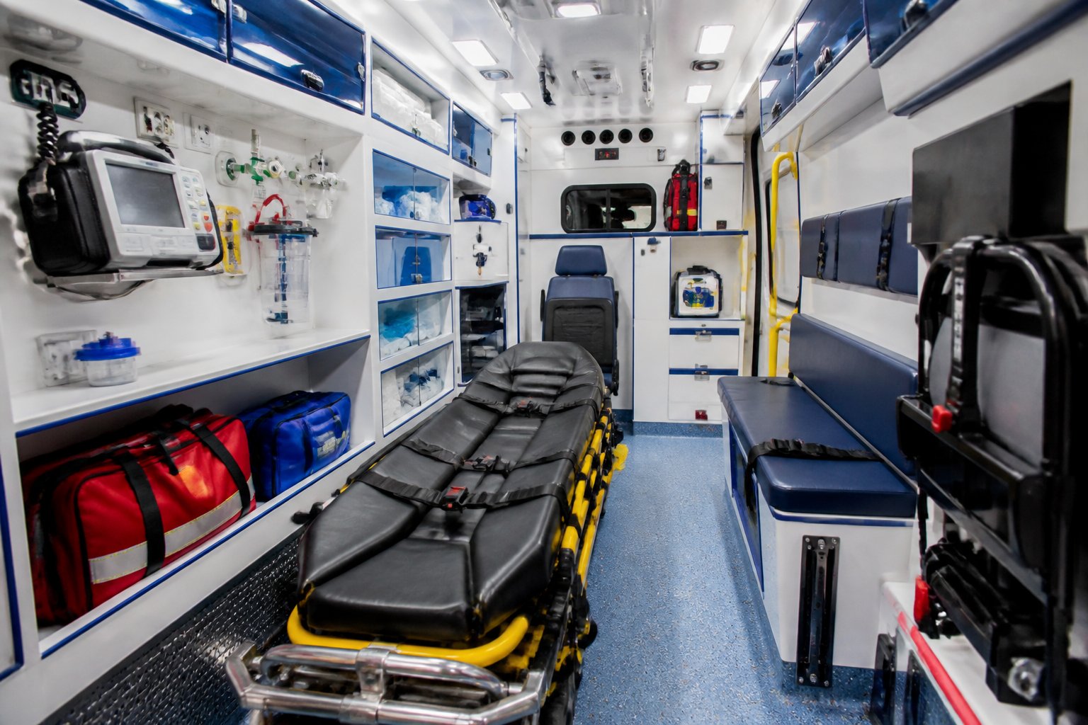 Interior de uma ambulância mostrando o ambiente interno com equipamentos médicos organizados e uma maca central.