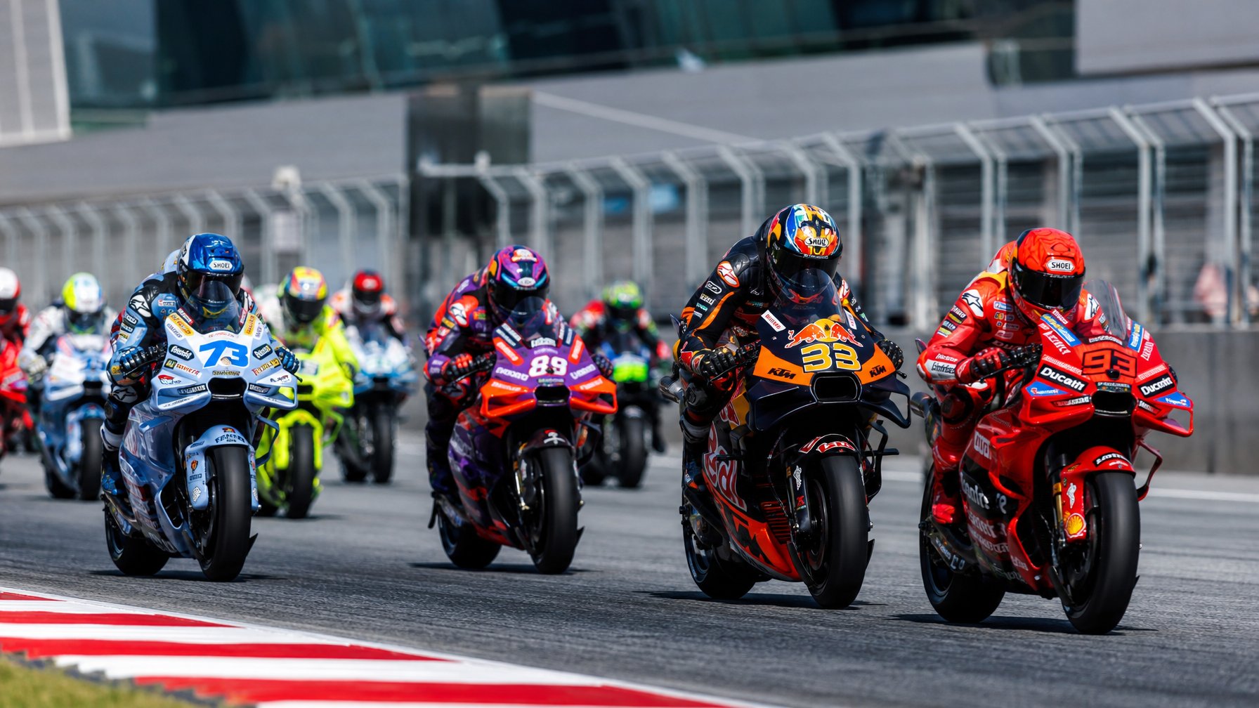 Beberapa pembalap MotoGP sedang bersiap di lintasan balap dengan motor mereka, mengenakan pakaian balap berwarna-warni dan helm, siap untuk memulai balapan.