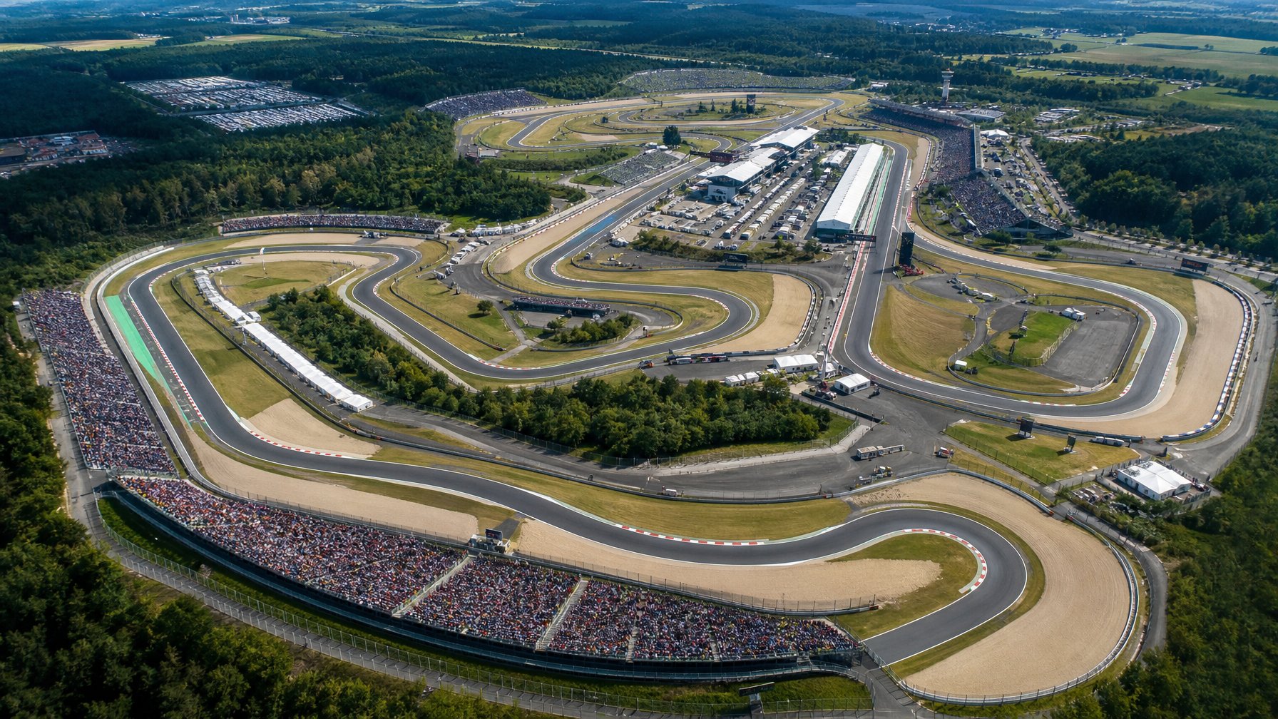 Pemandangan udara sirkuit balap Formula 1 dengan tikungan tajam dan tribun penonton yang penuh.