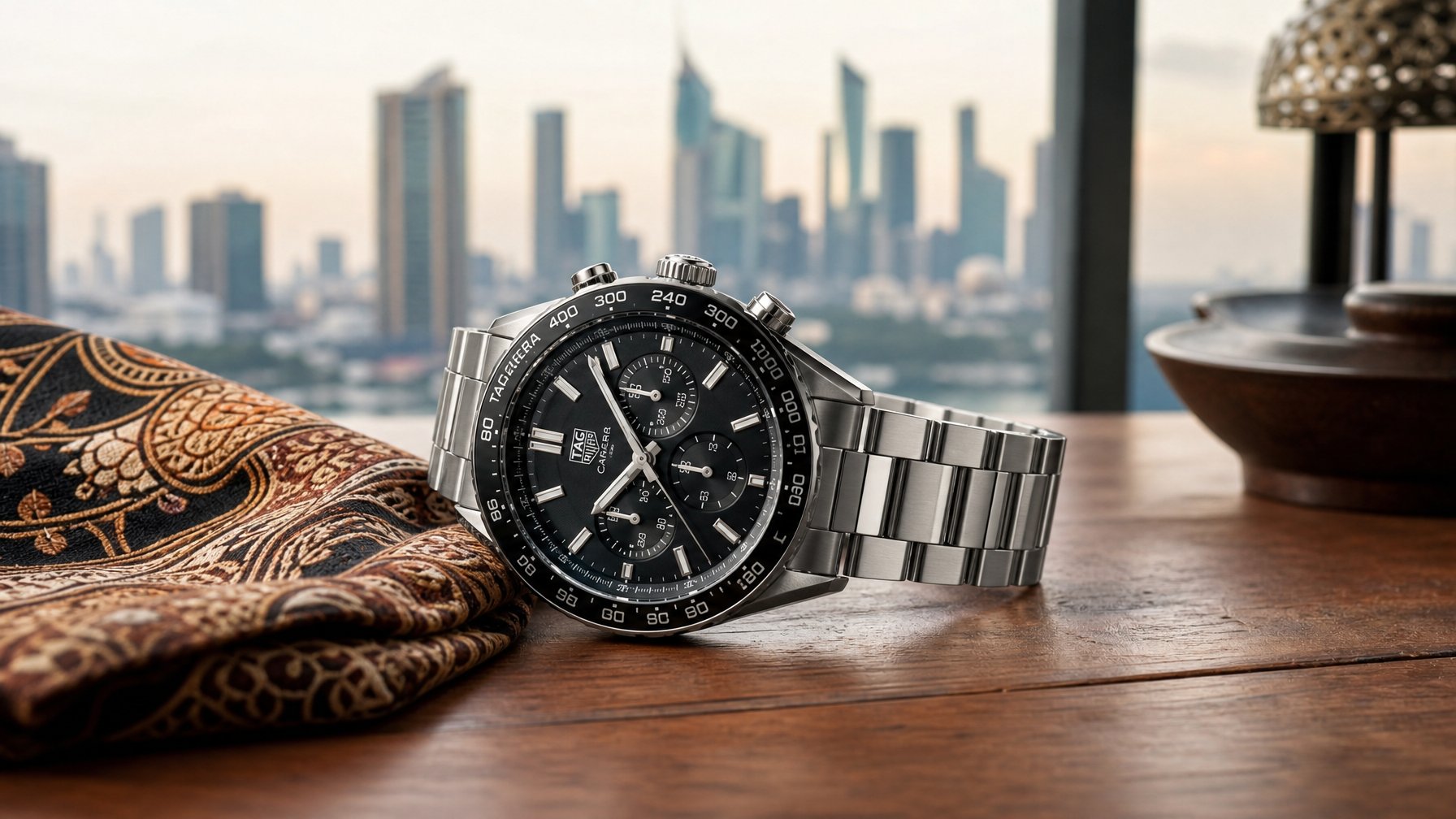 Jam tangan Tag Heuer mewah diletakkan di atas meja kayu dengan latar belakang elemen khas Indonesia dan pemandangan kota.