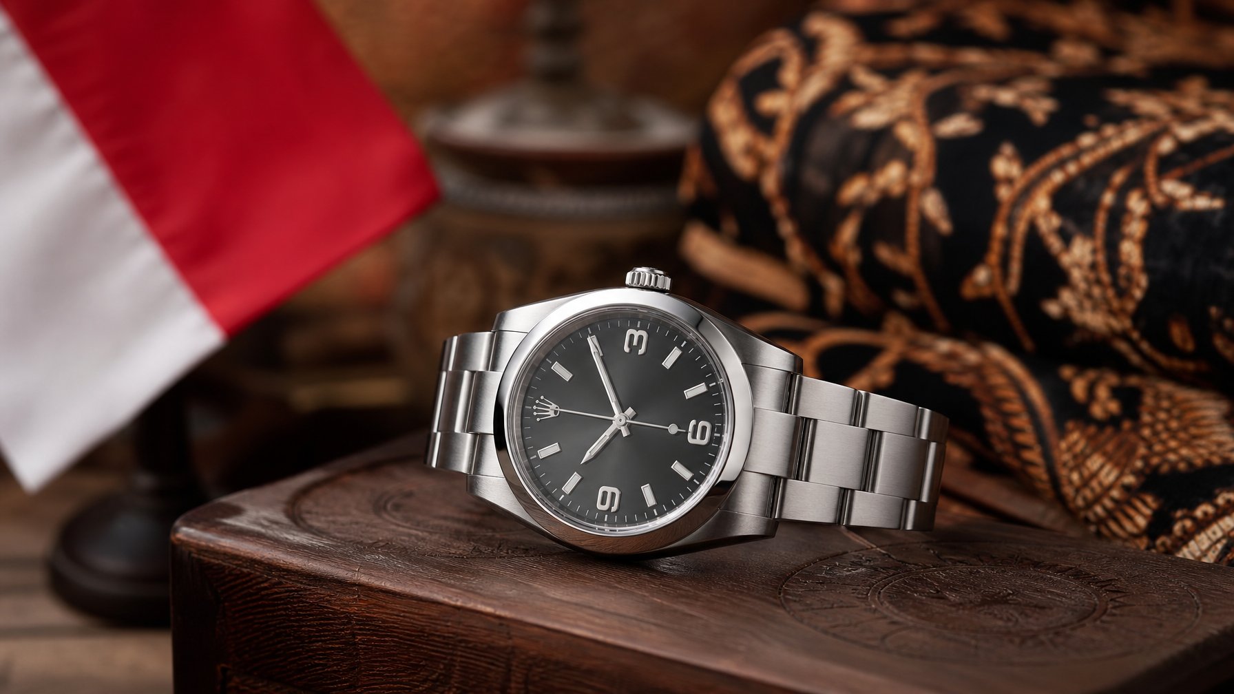 Jam tangan Rolex mewah diletakkan di atas permukaan kayu dengan latar belakang kain batik dan bendera kecil Indonesia.