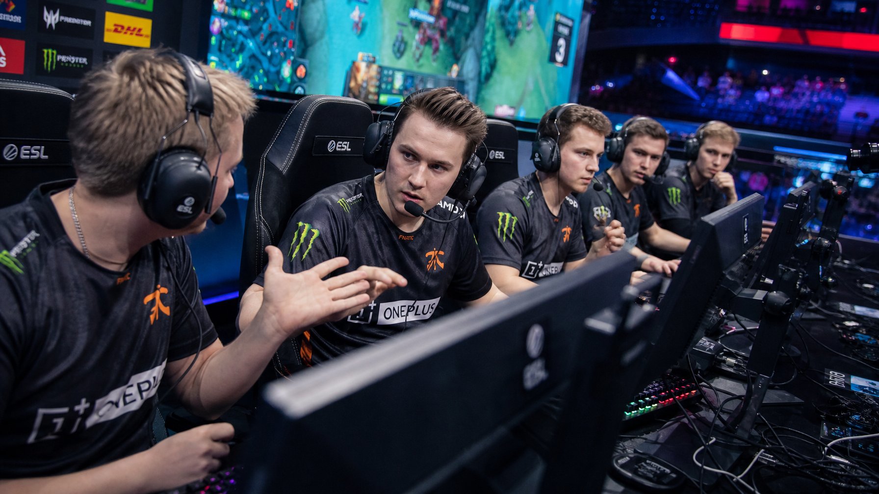 Tim esports sedang berkomunikasi dan berkoordinasi saat pertandingan Dota 2 dengan fokus dan peralatan gaming lengkap.