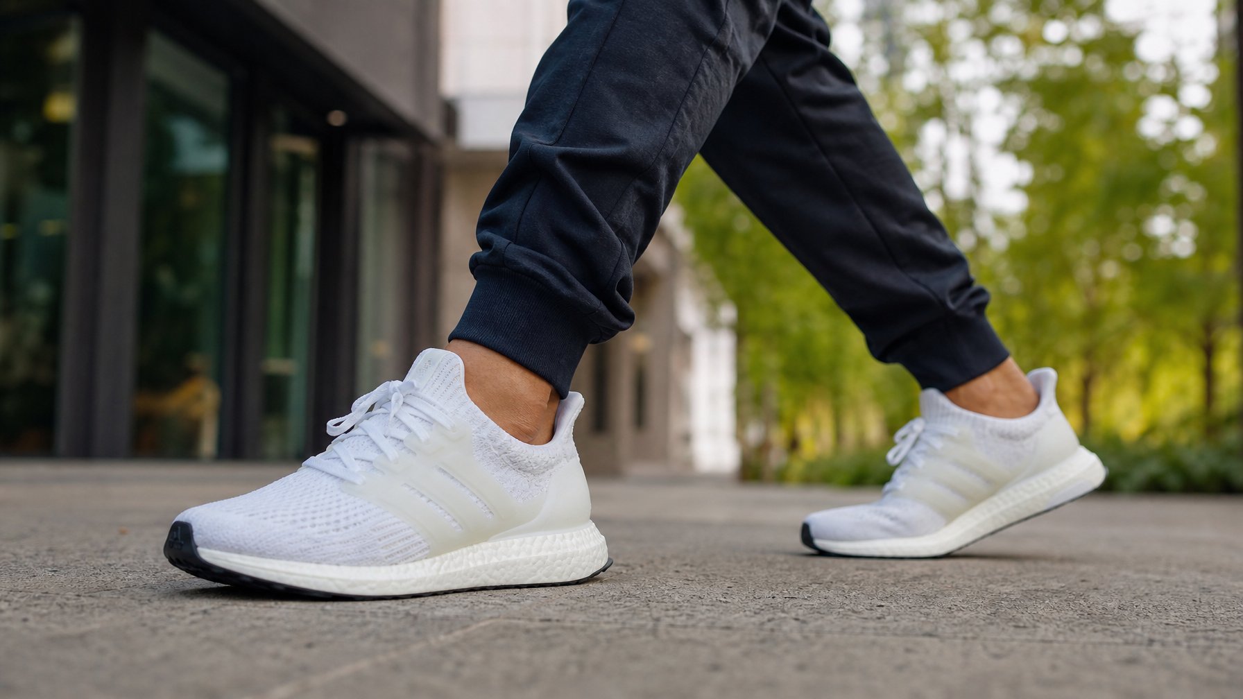 Seseorang berjalan di trotoar kota memakai sepatu Adidas Ultraboost terbaru.