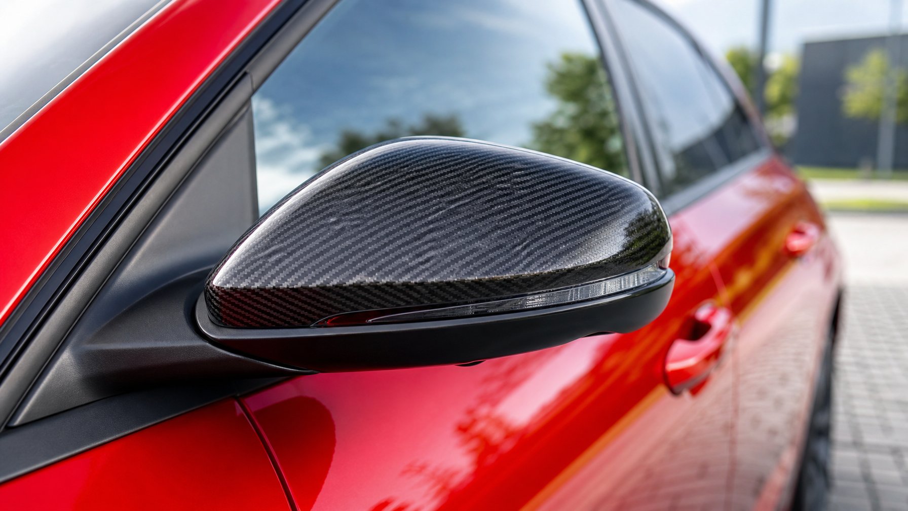Gambar close-up spion mobil dengan cover serat karbon di latar perkotaan.