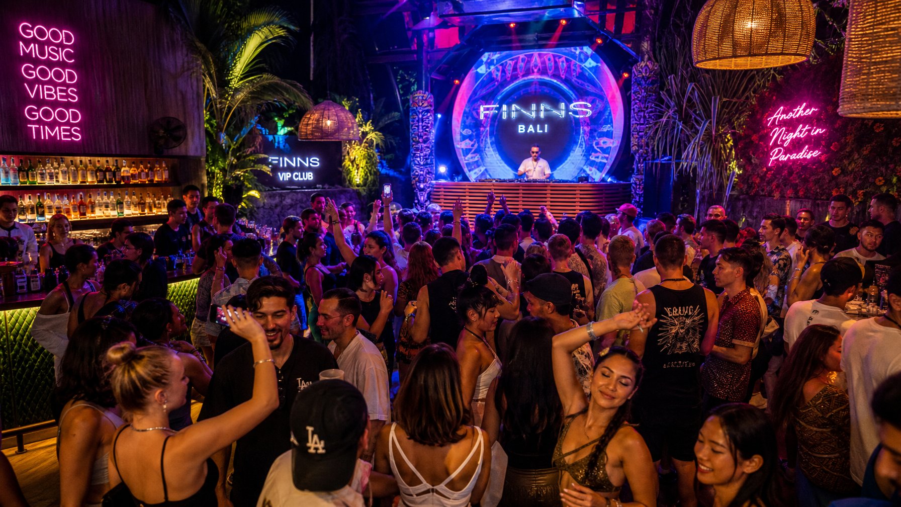 Suasana klub malam yang ramai dengan orang-orang menari dan bersenang-senang di Bali saat malam hari.