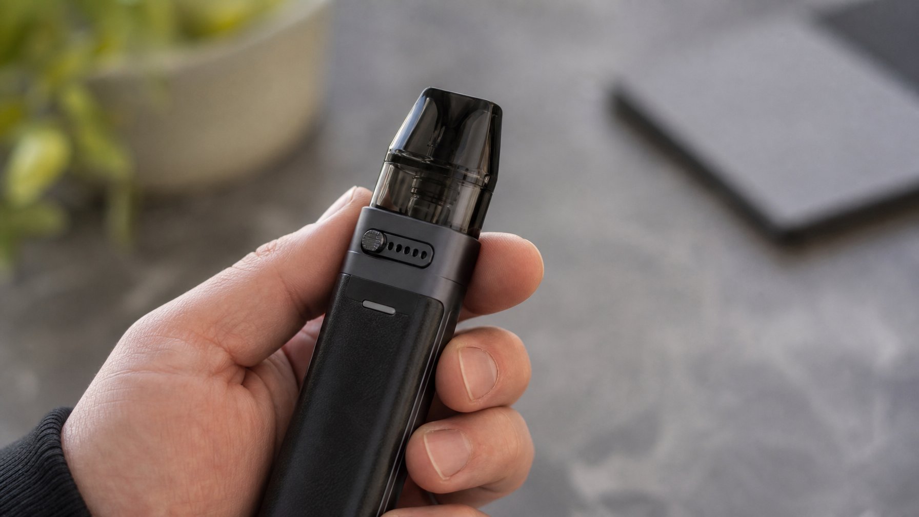 Gambar close-up sebuah perangkat vape pod modern yang dipegang oleh tangan, menampilkan mekanisme aliran udara yang dapat disesuaikan.