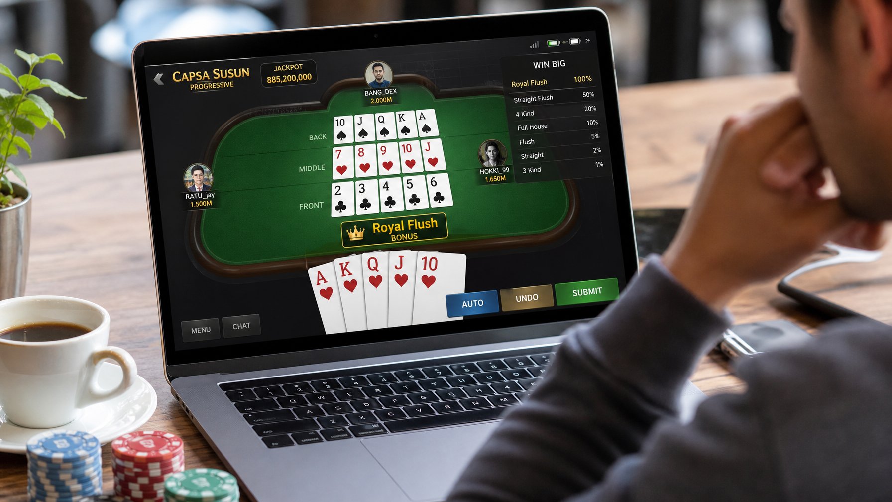 Seorang pemain sedang fokus bermain Capsa Susun online di depan layar laptop dengan kartu dan chip di meja.
