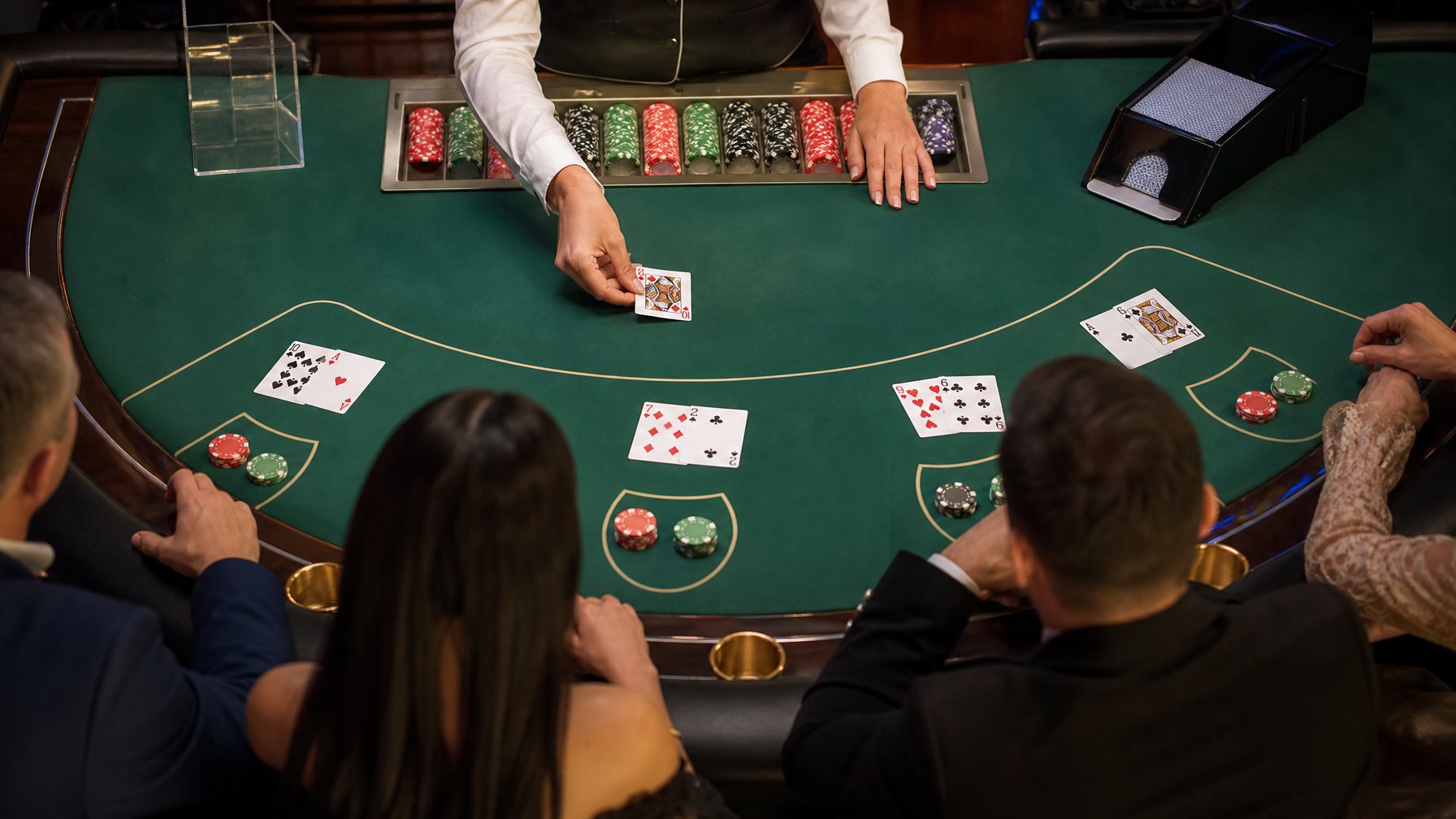 Meja blackjack dengan kartu, keping taruhan, dan tangan dealer yang sedang mengatur permainan.