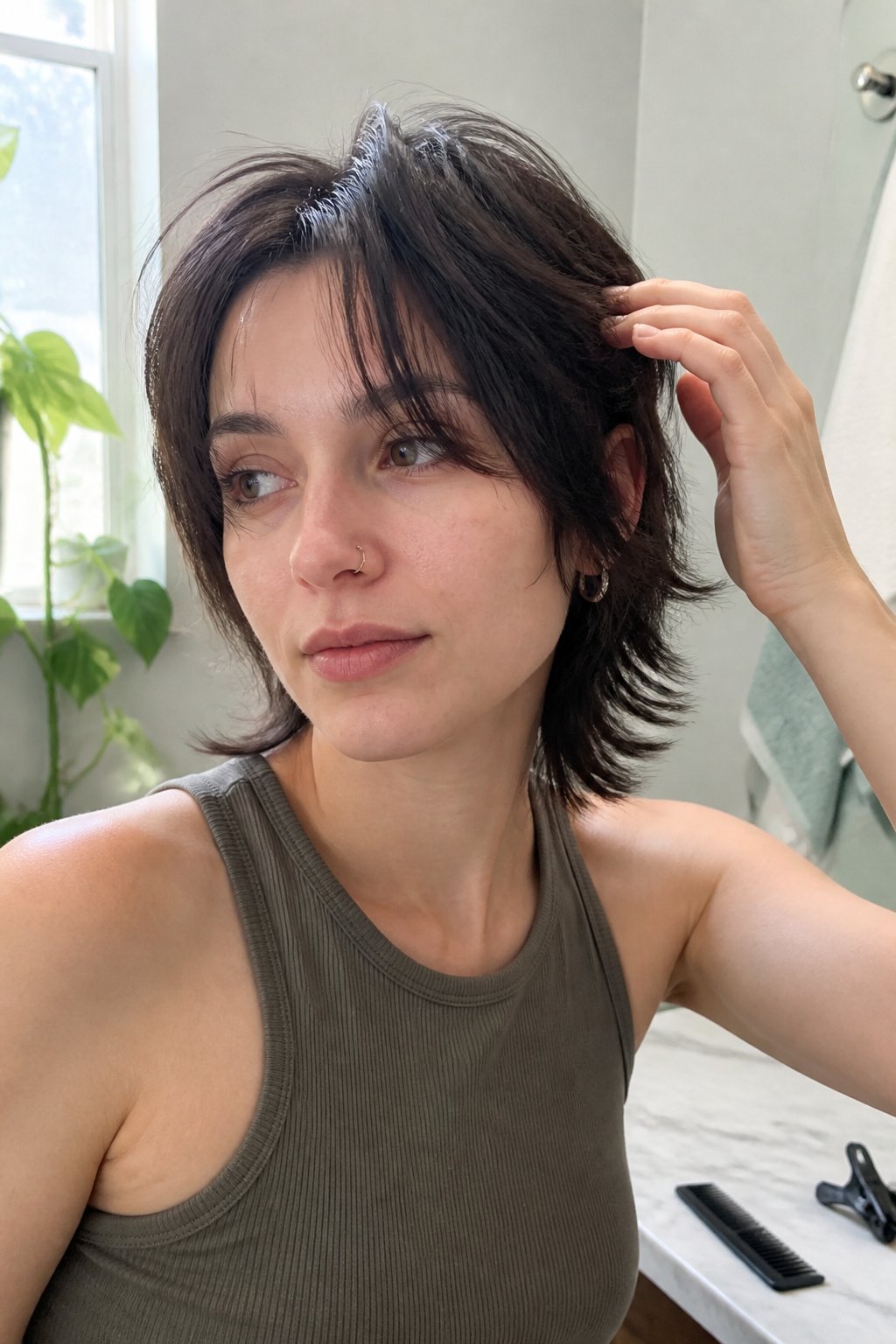 A person with a short layered wolf cut and curtain bangs stands in a naturally lit room.