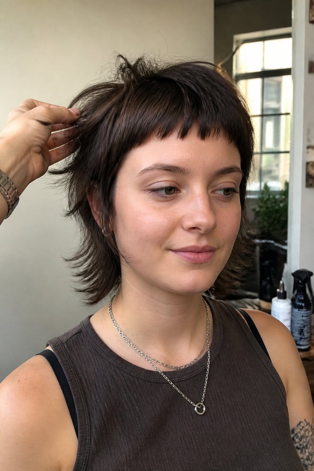 Person with a short layered wolf cut and micro bangs in a salon.