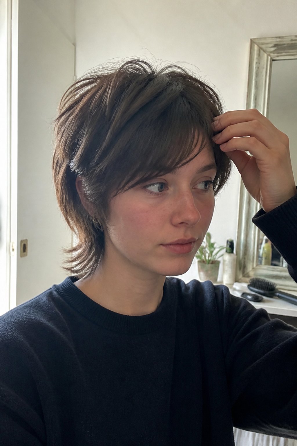 A person with a short layered wolf cut and side-swept bangs in a casual indoor setting.