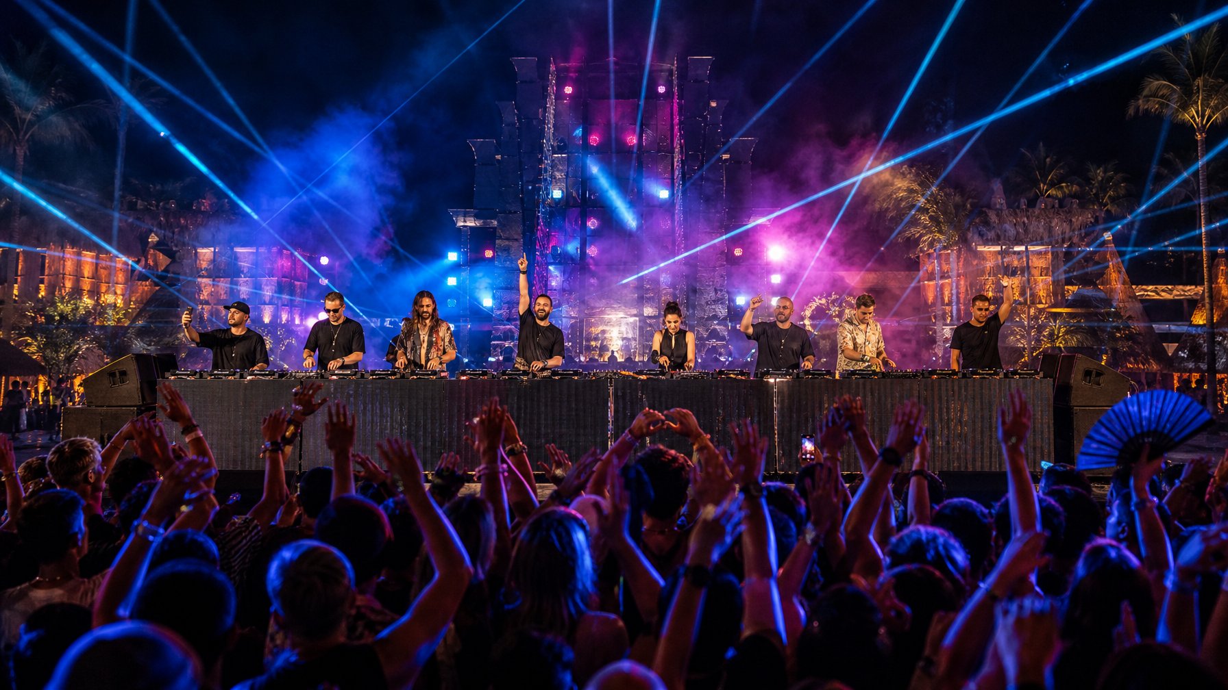 Para DJ internasional tampil di panggung festival malam dengan lampu warna-warni dan penonton yang antusias.