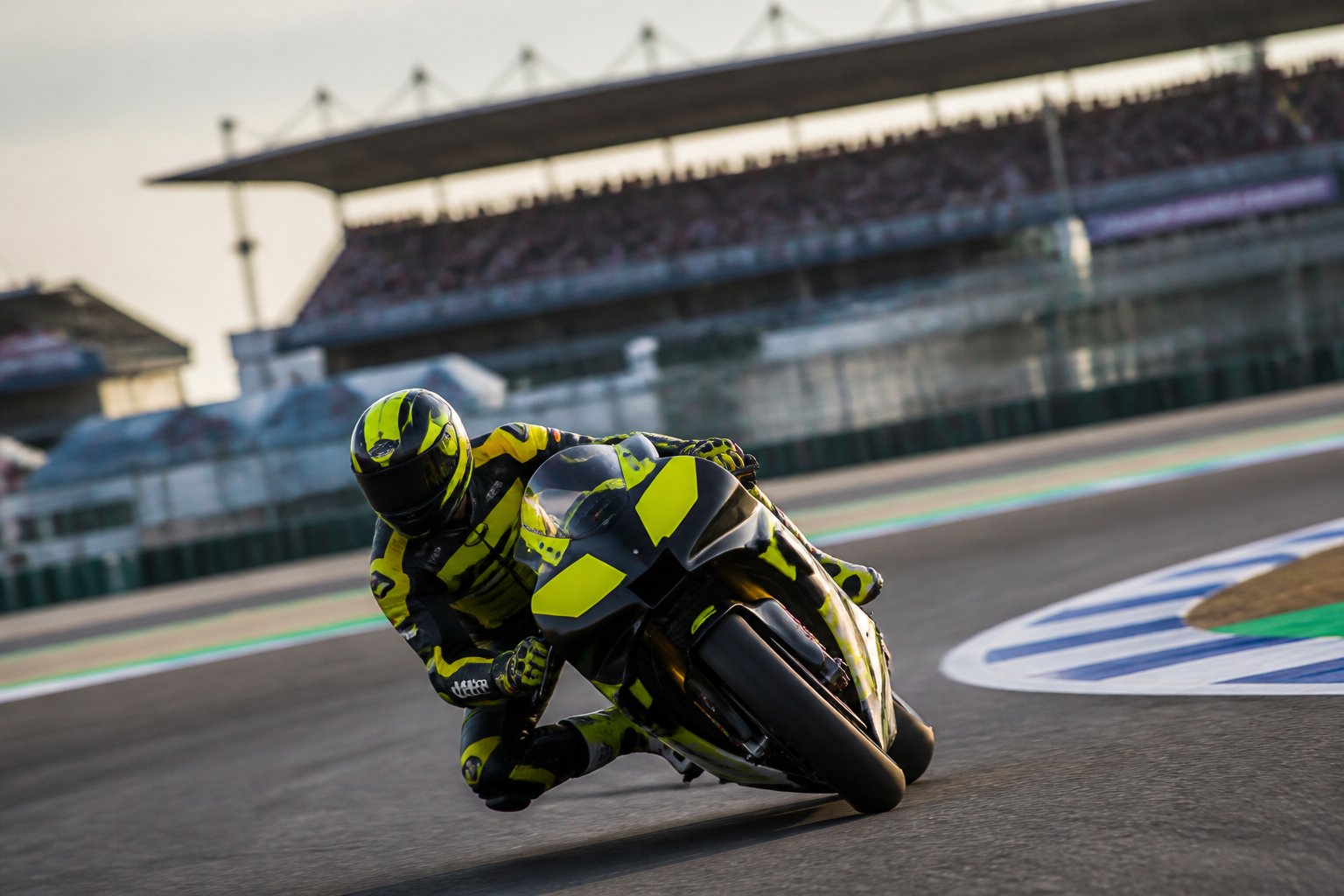 Pembalap MotoGP mengendarai motor balap berwarna kuning dan hitam di tikungan.