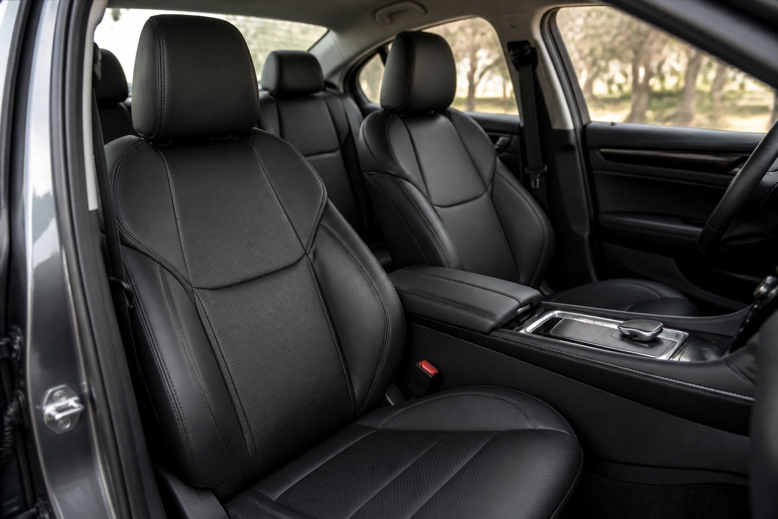 Interior mobil modern dengan jok berlapis kulit sintetis hitam yang rapi dan elegan.