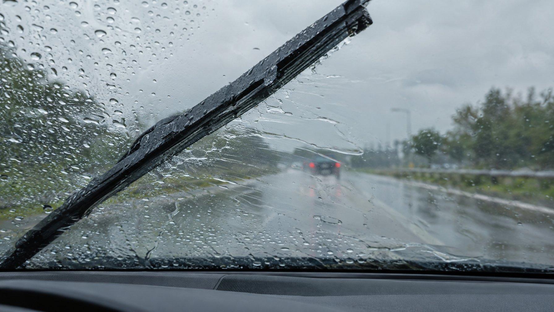 Wiper mobil menyisakan jejak dan genangan air di kaca depan saat hujan.