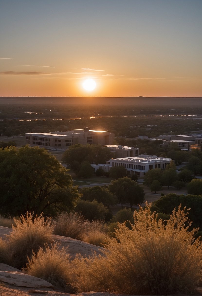 The sun sets behind the silhouette of the Waco Mammoth National Monument, with hotels nearby and the city's attractions in the distance