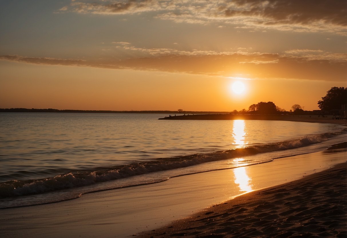 The sun sets over Lake Waveland Park Beach, casting a warm glow on the sandy shoreline and calm waters, perfect for beachcombers to explore