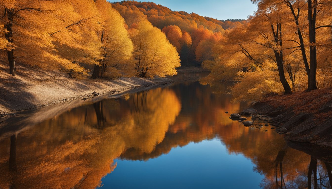 Golden leaves cover the ground, a winding river reflects the orange and red trees under a clear blue sky