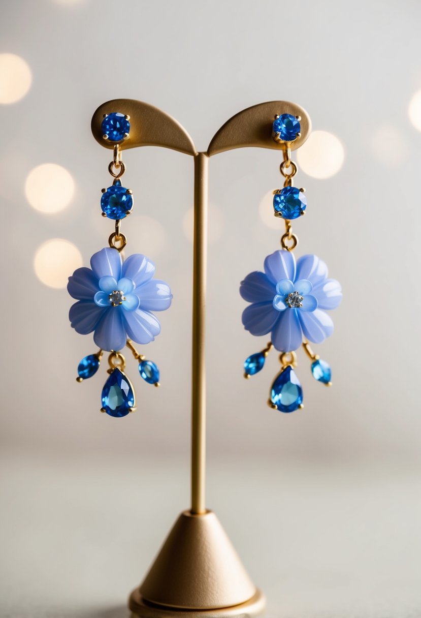 A delicate pair of periwinkle floral dangle earrings, accented with sparkling blue gemstones, hang from a display stand against a soft, neutral background