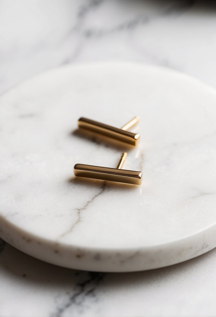 Two dainty gold bar studs on a white marble surface