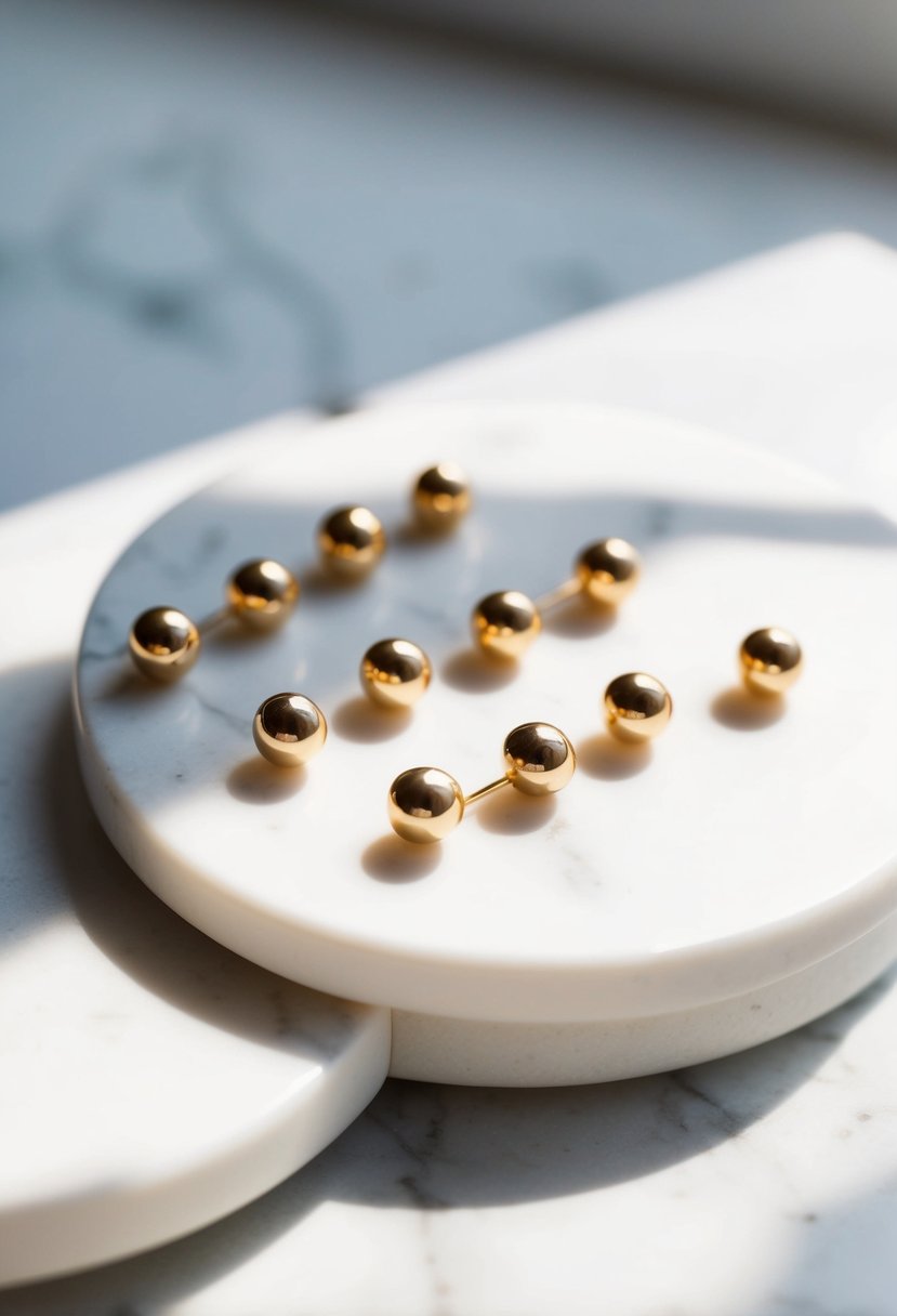 A simple, elegant display of minimalist gold studs arranged on a white marble surface, with soft, natural light casting a gentle glow on the earrings