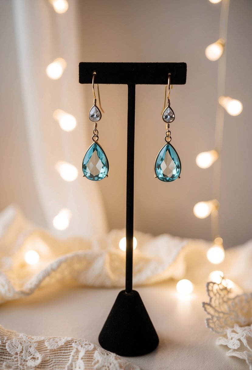 A pair of elegant teardrop dangle earrings suspended from a display stand, surrounded by soft lighting and delicate lace fabric